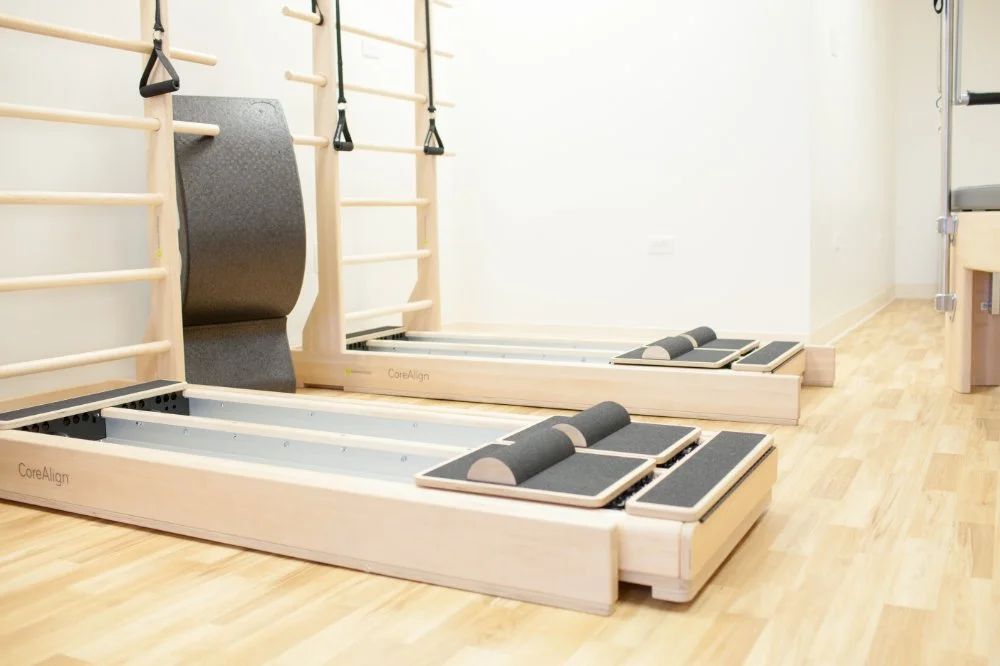 Rehabilitation room with wooden therapeutic exercise equipment including parallel bars, balance boards, and wall-mounted climbing bars on a light wooden floor.