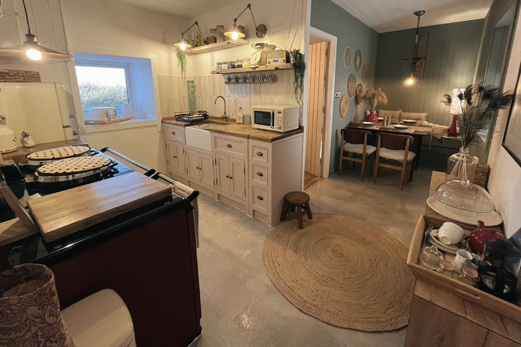 Cozy kitchen and dining area with white cabinets, a microwave, a stove, and a round jute rug.