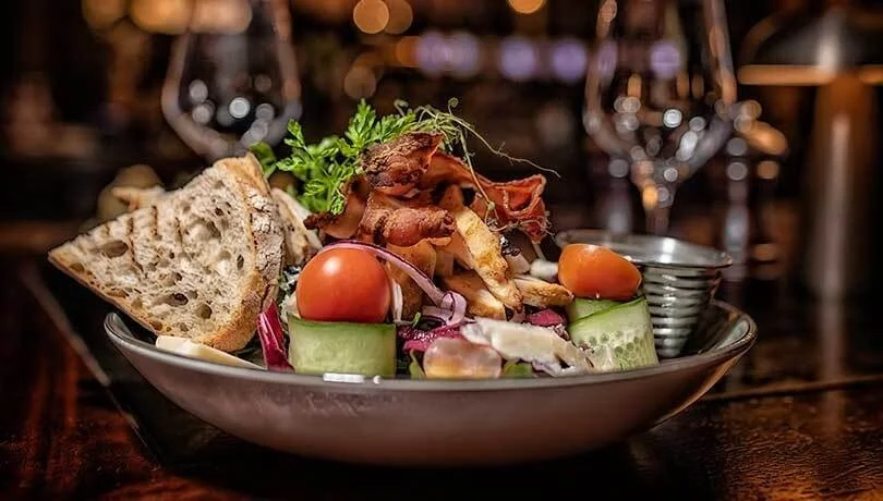 Bilde av en salat med bacon og grønnsaker og brød ved siden av på Havnelageret Moss