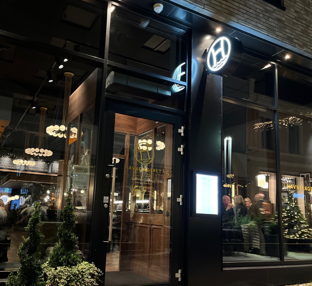 Bilde inngangsdøra til Havnelageret Moss på kveldstid - lysskilt