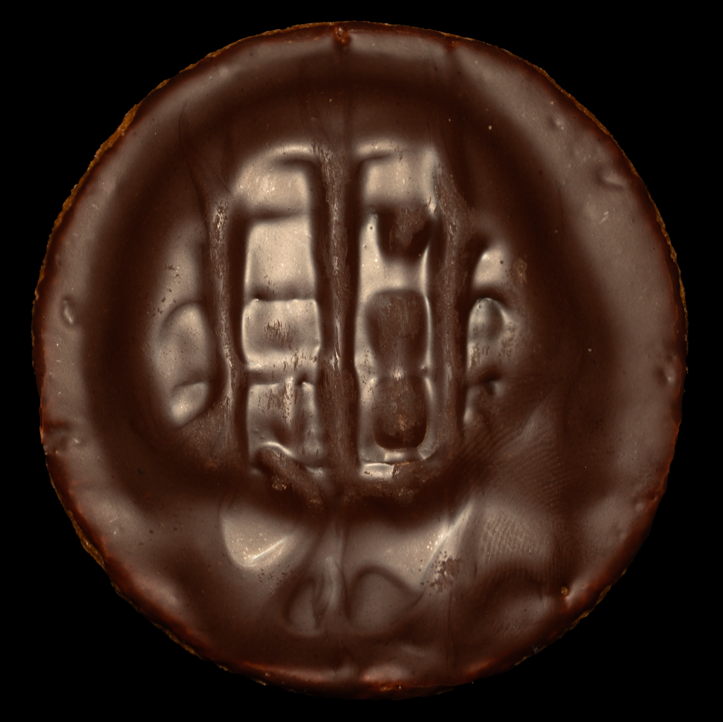 Close-up of a round chocolate-covered candy with the letters 'E&F' embossed on top.