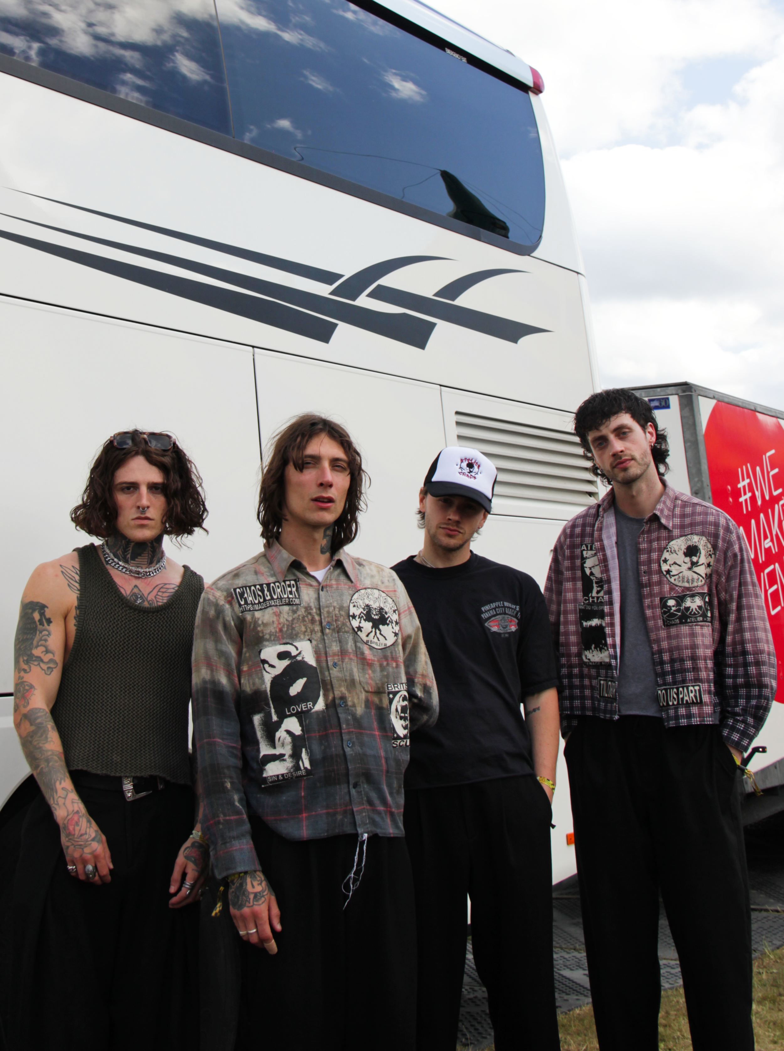 Back stage photos of the band Mouth Culture in front of a white tour bus, taken behind the scenes at Slam Dunk Festival 2025, Temple Newsam in Leeds. Three members are wearing clothing by the independent clothing brand Atelier based in Sheffield.