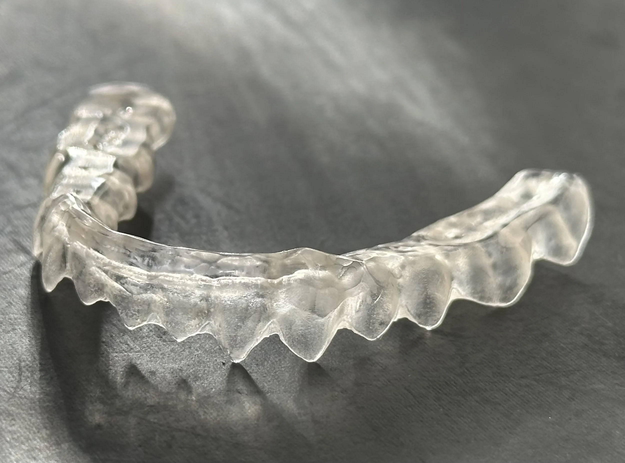 A clear dental night guard on a dark surface.
