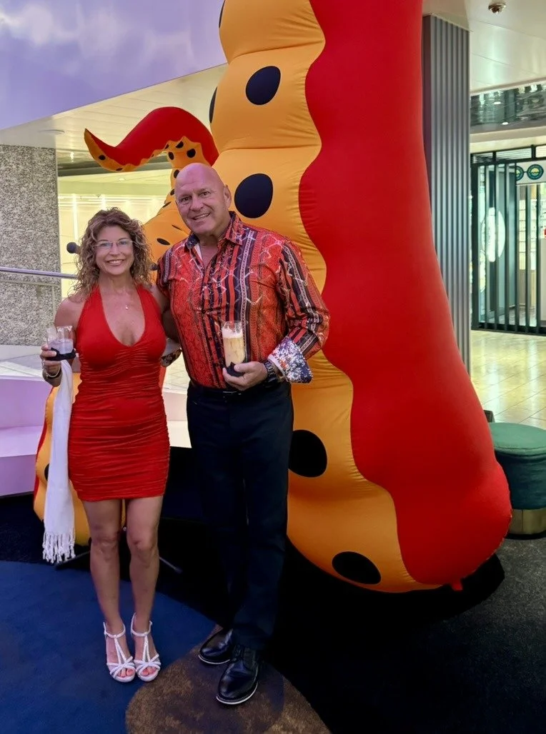 Jim and Mary Mincy dressed in red for Scarlet Night beside a giant red tentacle on Resilient Lady