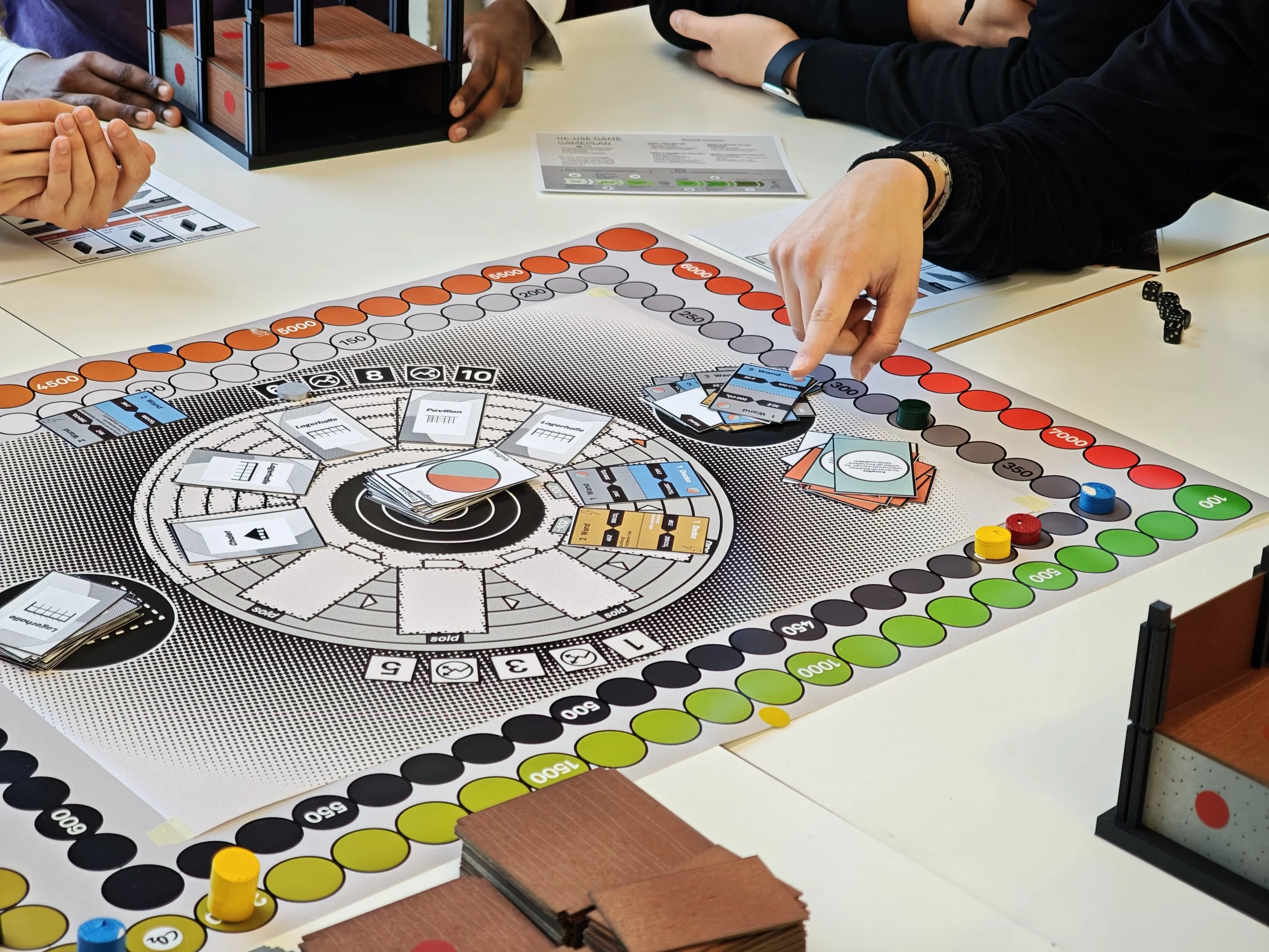 Menschen spielen ein Brettspiel an einem Tisch, mit Spielkarten, Spielfiguren, und einem Spielbrett.