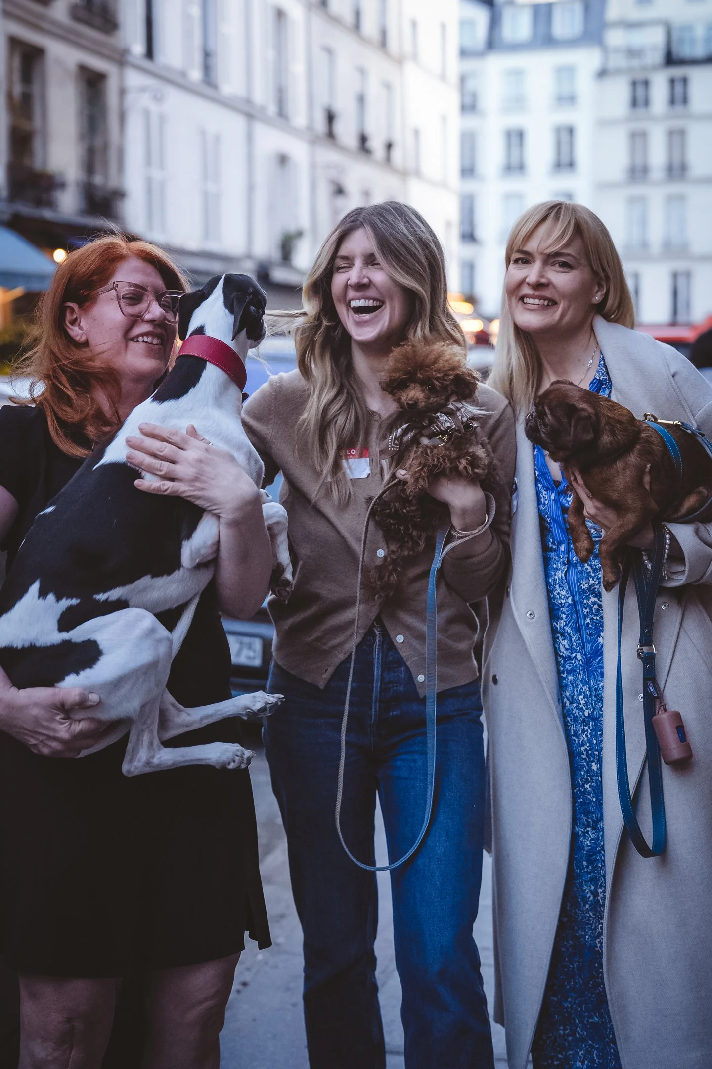 Lifestyle portrait of three women with small dogs on a Paris street.