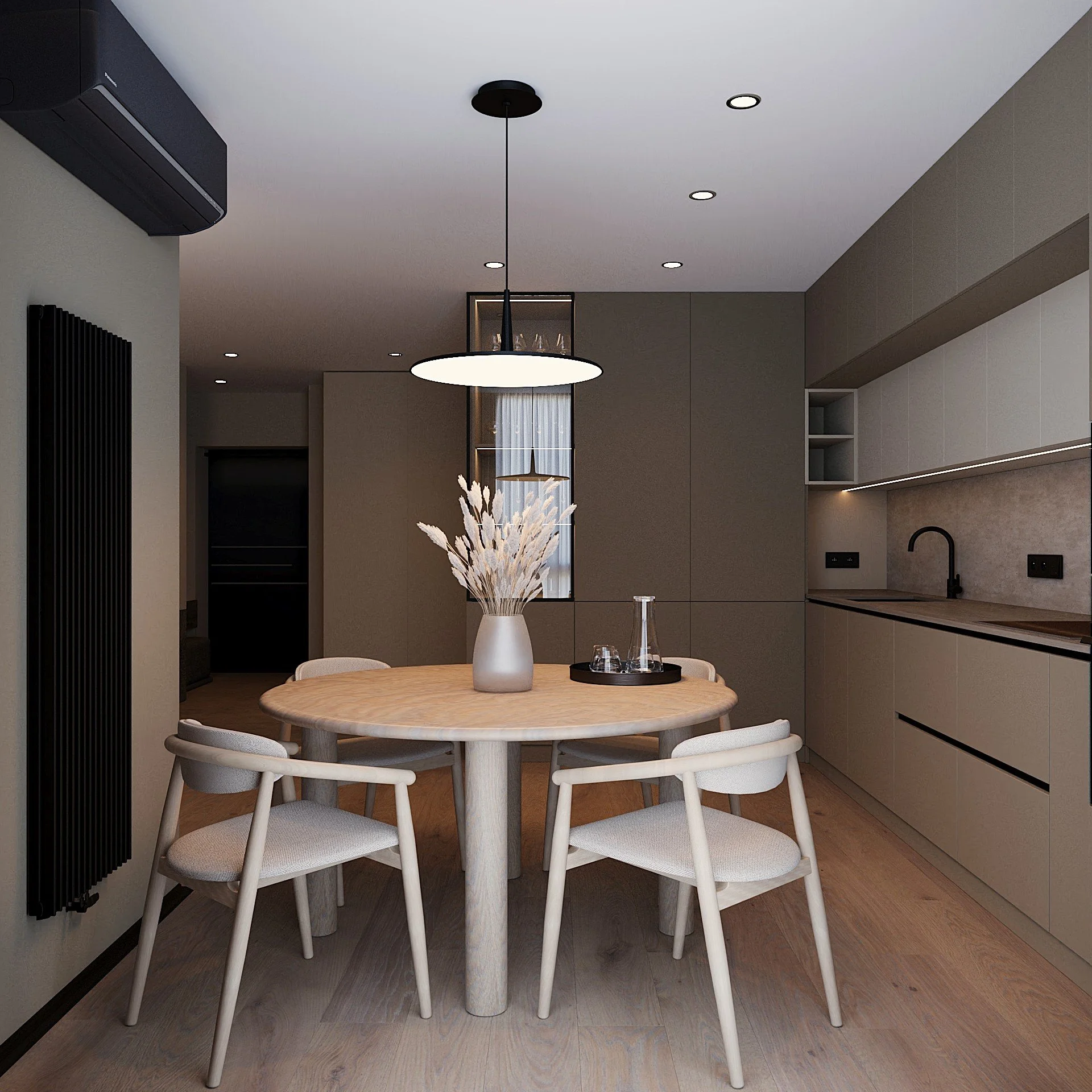 Modern kitchen and dining area with a round wooden table, four light-colored chairs, a vase with dried flowers, a hanging light, and minimalist cabinetry.