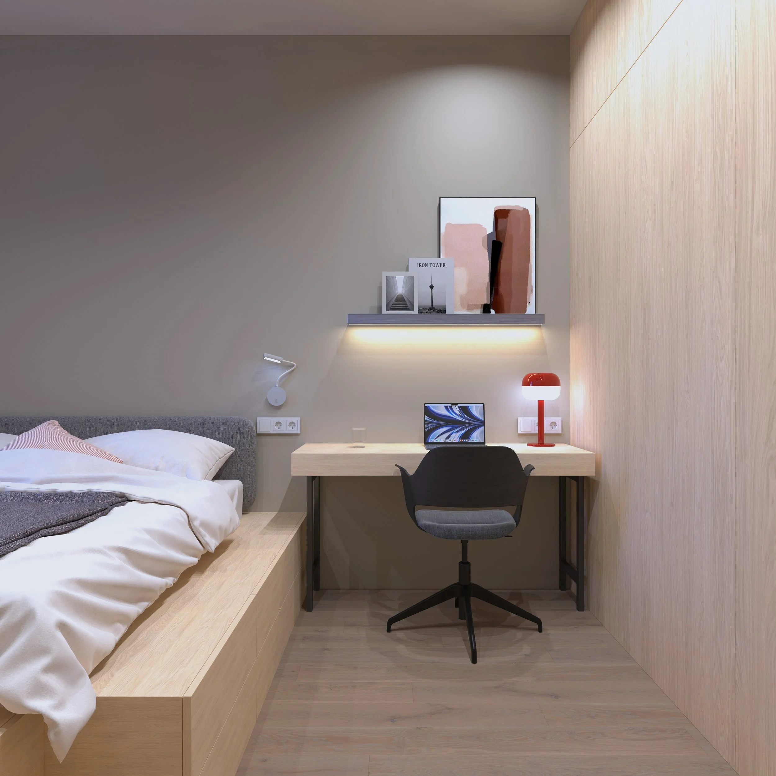 Modern bedroom with a bed on the left, a desk with a computer and a red lamp on the right, a wall-mounted shelf with artwork above the desk, and a light-colored wooden wall on the right.