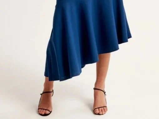 Woman in a blue dress with an asymmetrical hemline that is longer on her right and shorter on her left, creating a diagonal hemline