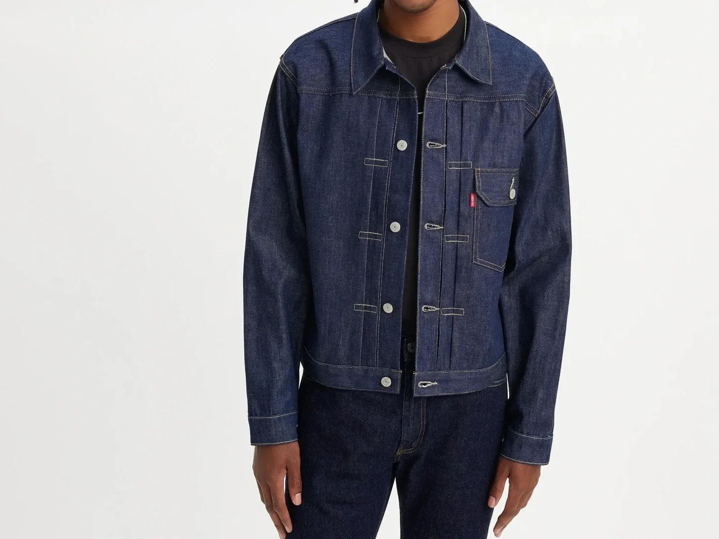 Man in a dark wash denim jacket with a single chest pocket