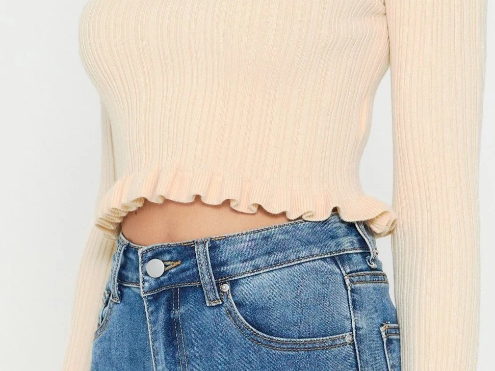 Woman in an ivory crop top with a ruffled lettuce hem