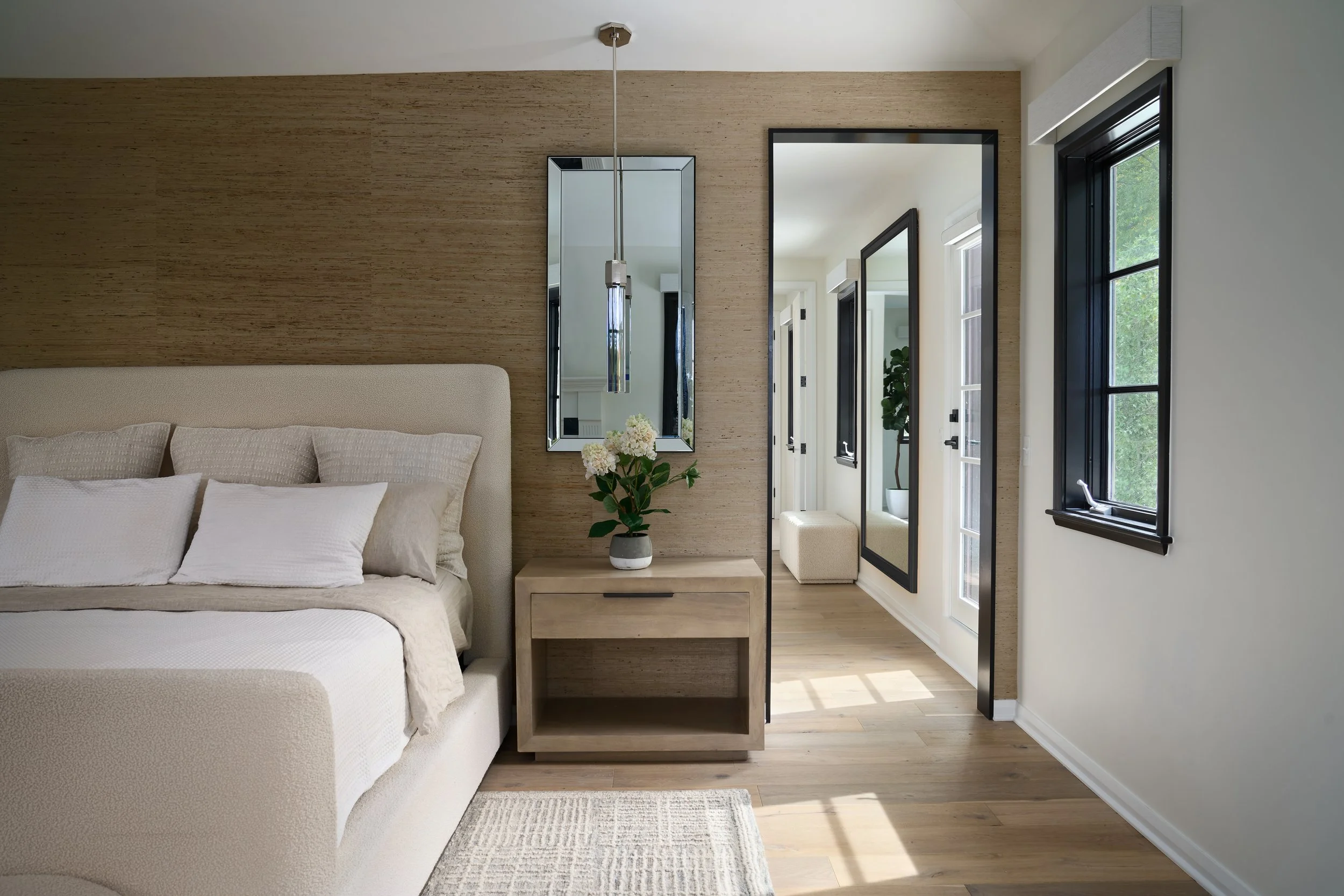 This serene primary bedroom in a luxury Bexley, Ohio full home remodel was designed by Benham & Co Interior Design, a premier Columbus Ohio interior design firm specializing in full-service residential design. Featuring warm natural textures, custom 
