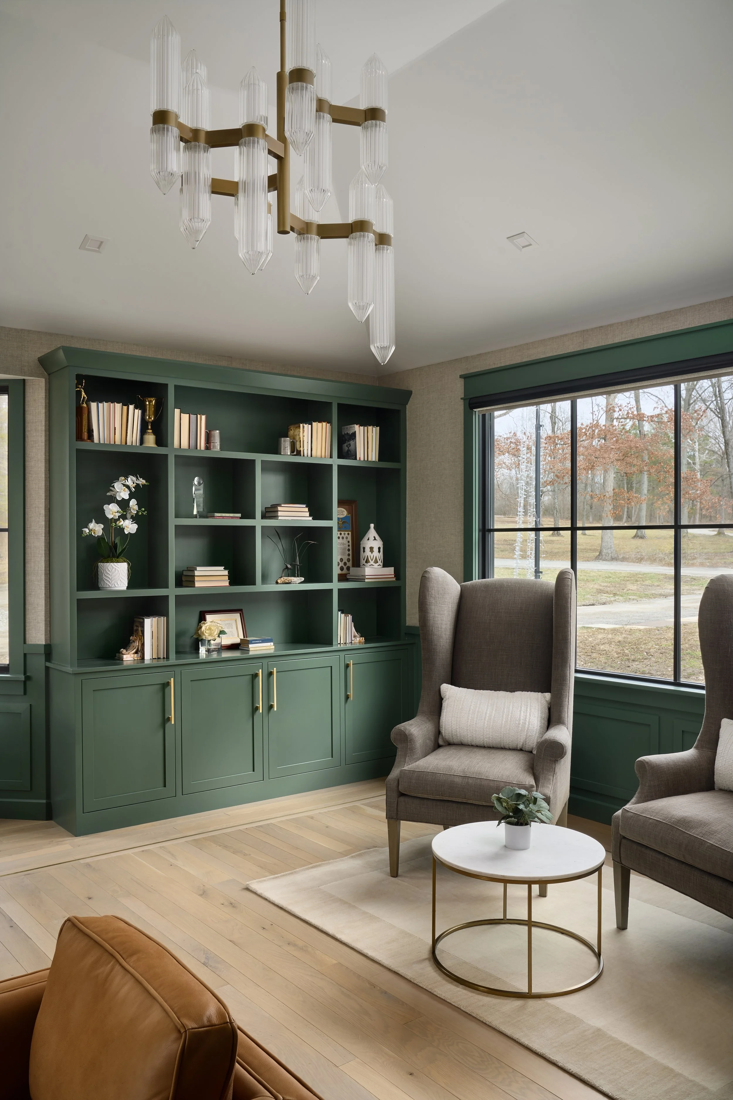 This custom home office and living space by Benham & Co Interior Design, a premier Columbus Ohio interior designer, showcases a sophisticated approach to luxury residential interior design in Westerville, Ohio. Rich green built-in cabinetry creates a