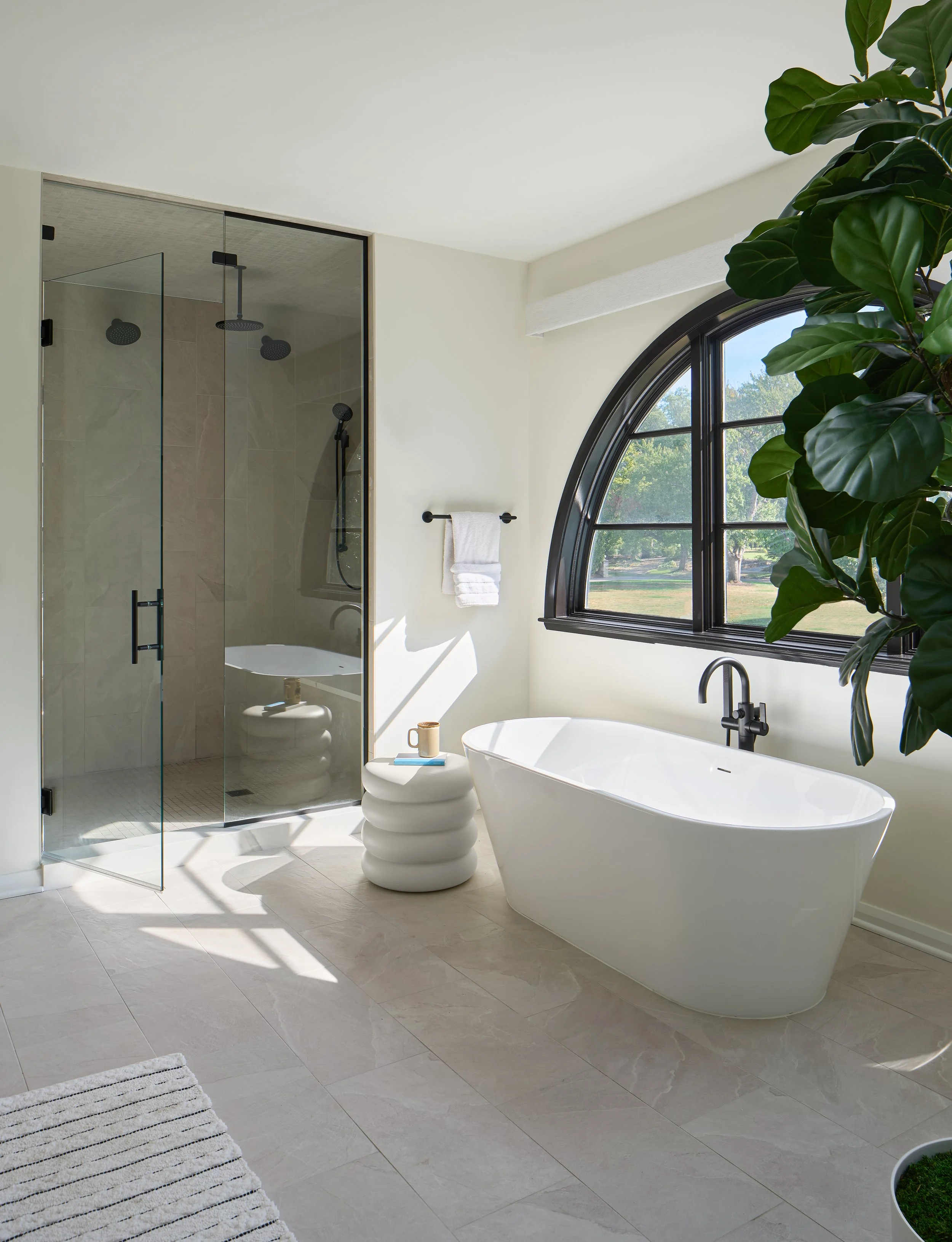 This spa-inspired primary bathroom in a luxury Bexley, Ohio full home remodel was designed by Benham & Co Interior Design, a premier Columbus Ohio interior design firm specializing in full-service residential design. Featuring a sculptural freestandi