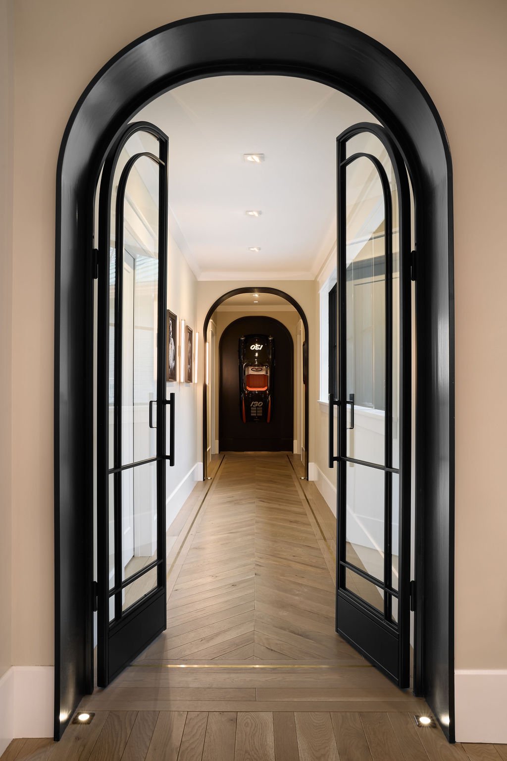 This custom hallway entry by Benham & Co Interior Design, a leading Columbus Ohio interior designer, showcases a refined approach to luxury residential interior design in Westerville, Ohio. Framed by a dramatic arched opening and steel-framed glass d