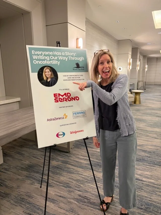 Woman smiling and pointing at a conference sign in a hotel hallway.