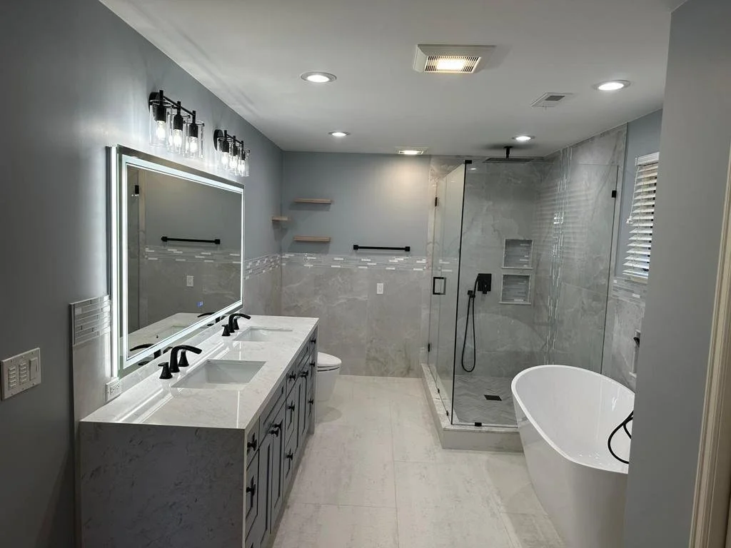 Modern bathroom with double vanity, large mirror, walk-in shower, and standalone bathtub.