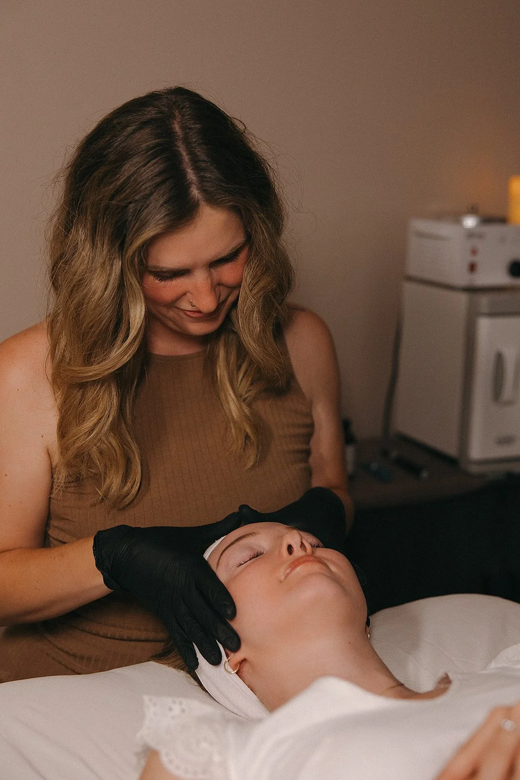 A woman receiving a facial treatment from a skincare professional in a clinic.