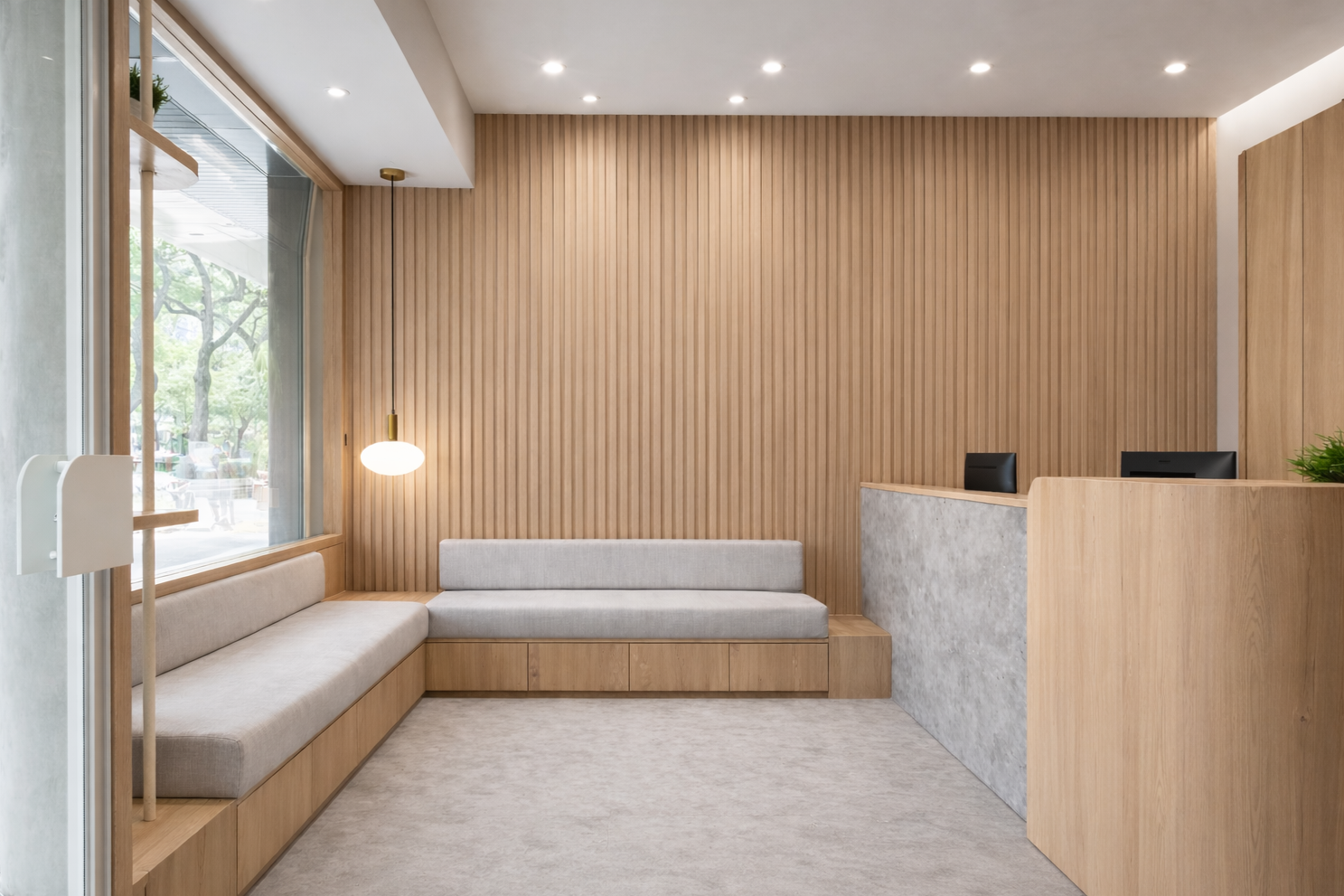 Modern reception area with wood-paneled wall, L-shaped beige sofa, gray cushion, pendant light, large window with outdoor view, and reception desk with black chairs.