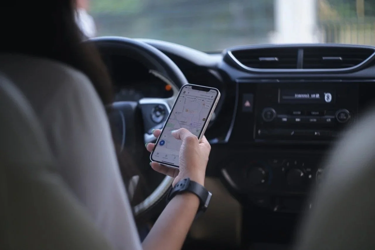 Frau am Steuer nutzt Smartphone während der Fahrt – Symbol für Ablenkung am Steuer vor Einführung des Schuldt Safety Fahrerassistenzsystems