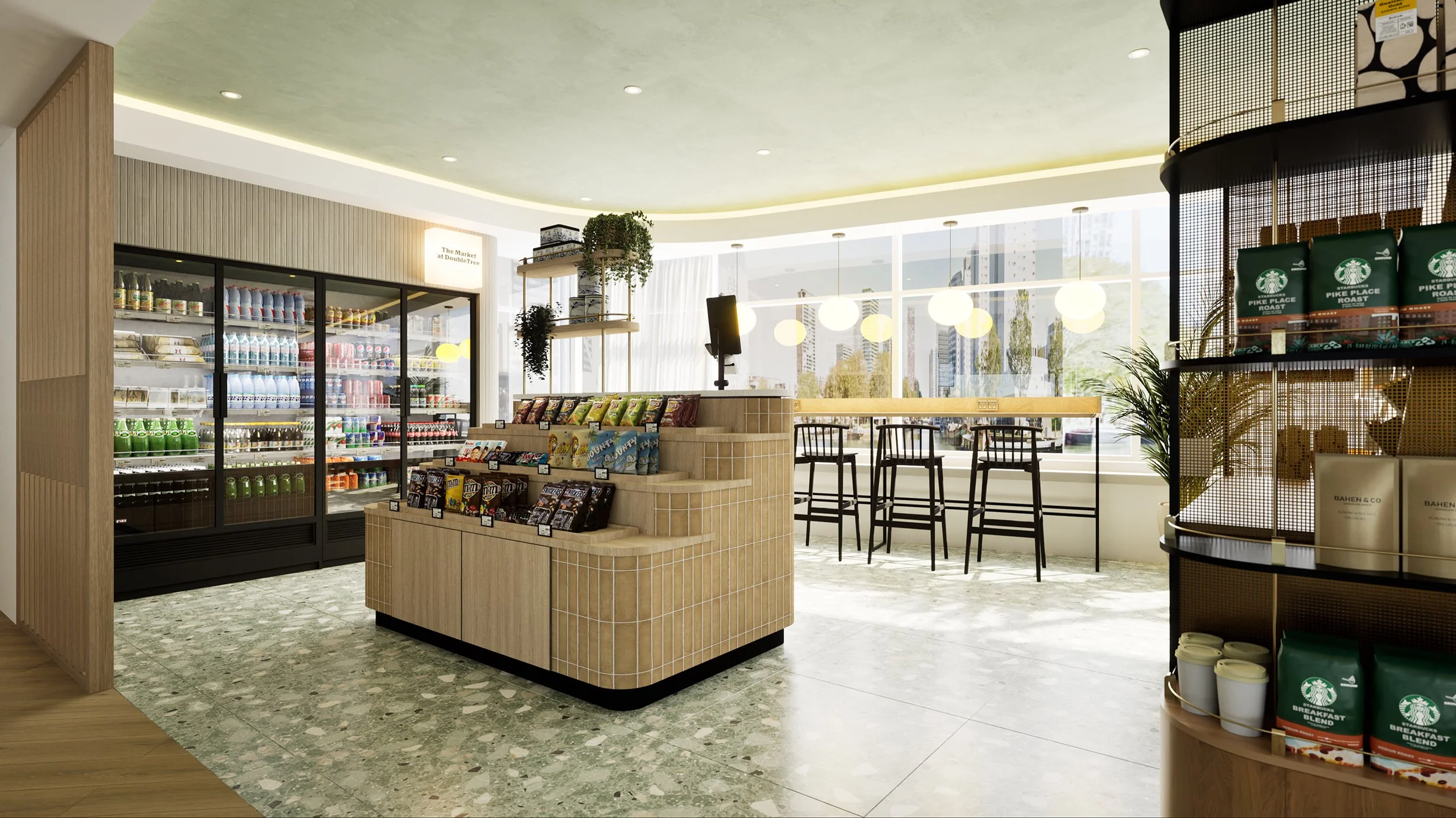 Inside a retail coffee shop with a refrigerated display of bottled drinks on the left, a small display of snacks in the center, and a seating area with tall chairs by large windows on the right. There are plants, shelves, and hanging lights in a modern, bright setting.