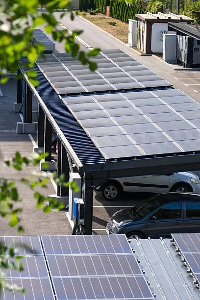 Voitures garées sous un parking avec des panneaux solaires sur le toit, dans une zone résidentielle ensoleillée.