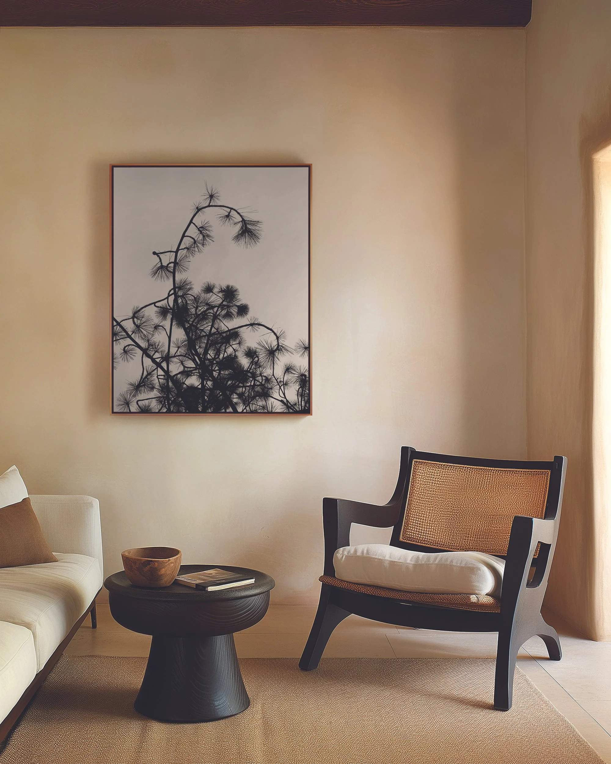 A photograph of a neutral and modern room with a large framed print of a black and white abstract photograph of curling branches of a musical pine tree; this is a limited edition print entitled Musical Pine