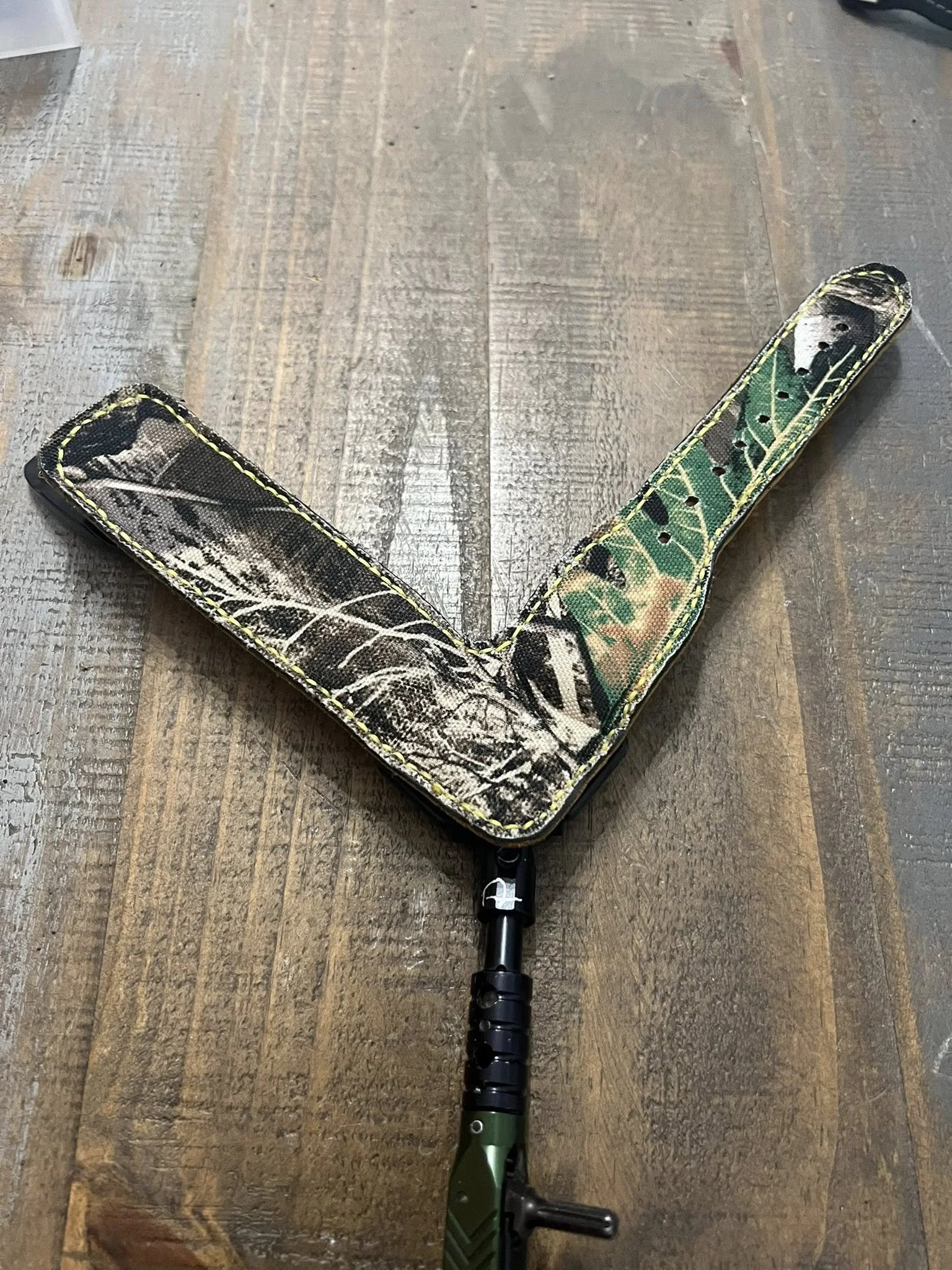 Hunting shotgun with camouflage cover resting on wooden floor.