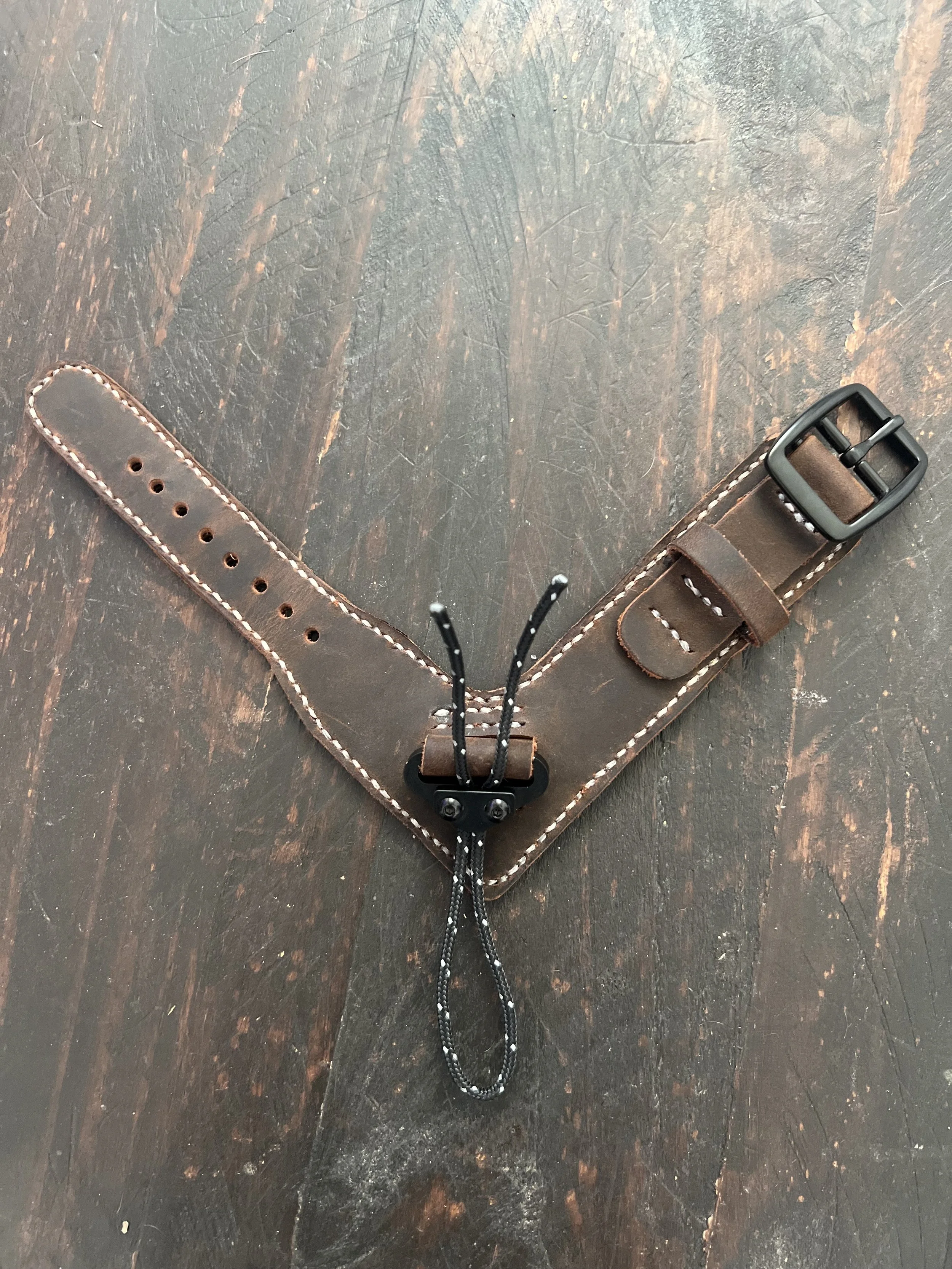 A leather dog collar with a buckle and adjustable strap, featuring a black plastic quick-release buckle and a black drawstring cord.