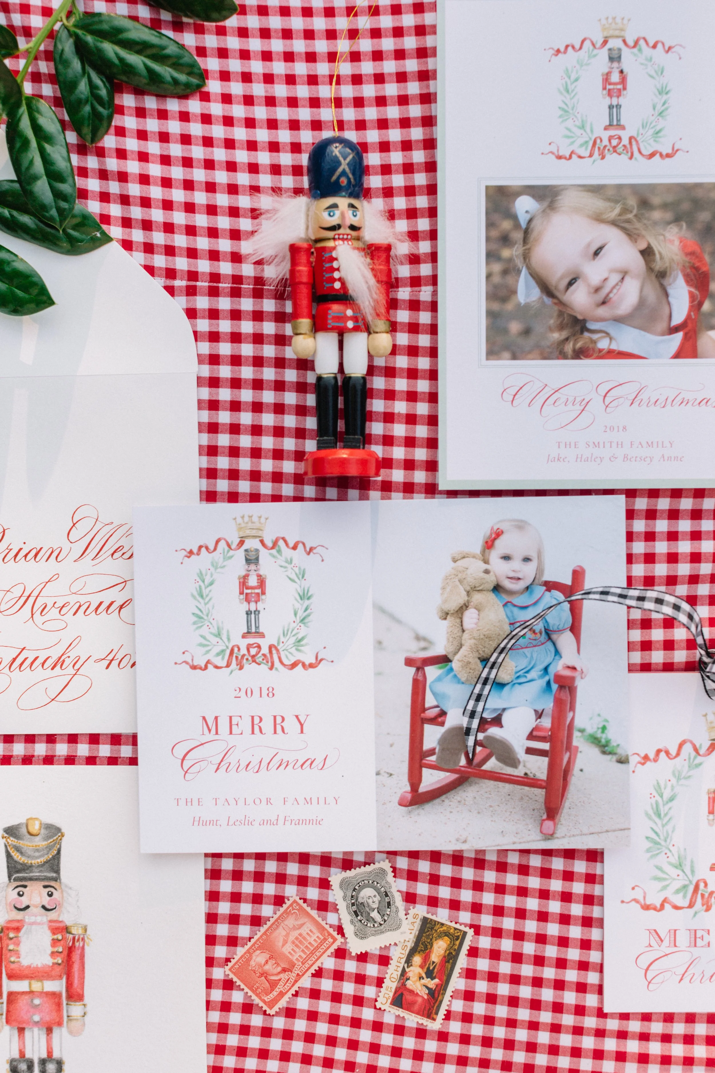 A holiday display featuring a Christmas-themed photo collage, vintage nutcracker figurine, holiday greeting cards, and vintage postage stamps on red and white checkered fabric background.