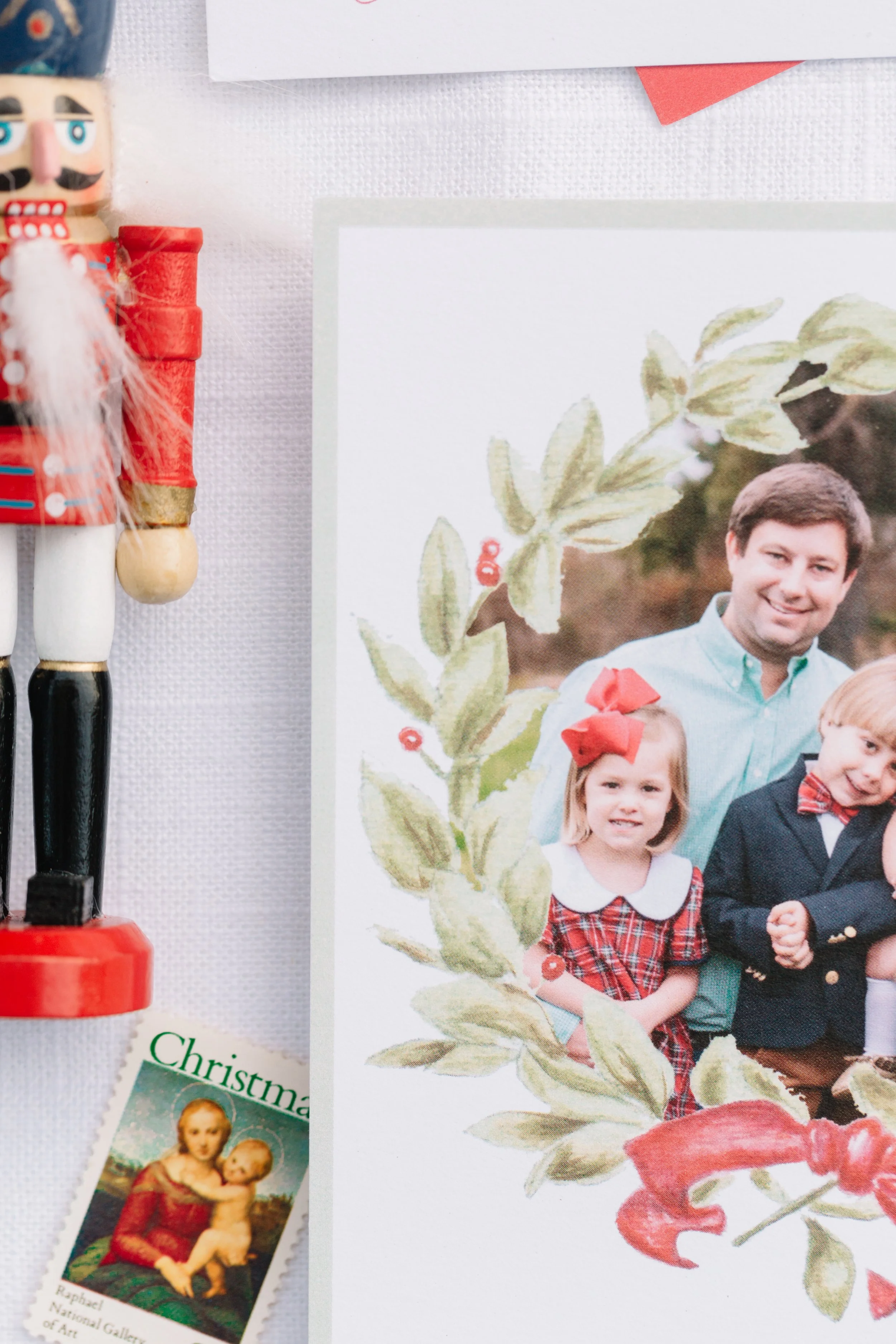 Close-up of a holiday photo of a man and children, partially obscured by Christmas decorations and a printed image of a nativity scene, including a small nutcracker figurine, a train ornament, and a Christmas card.