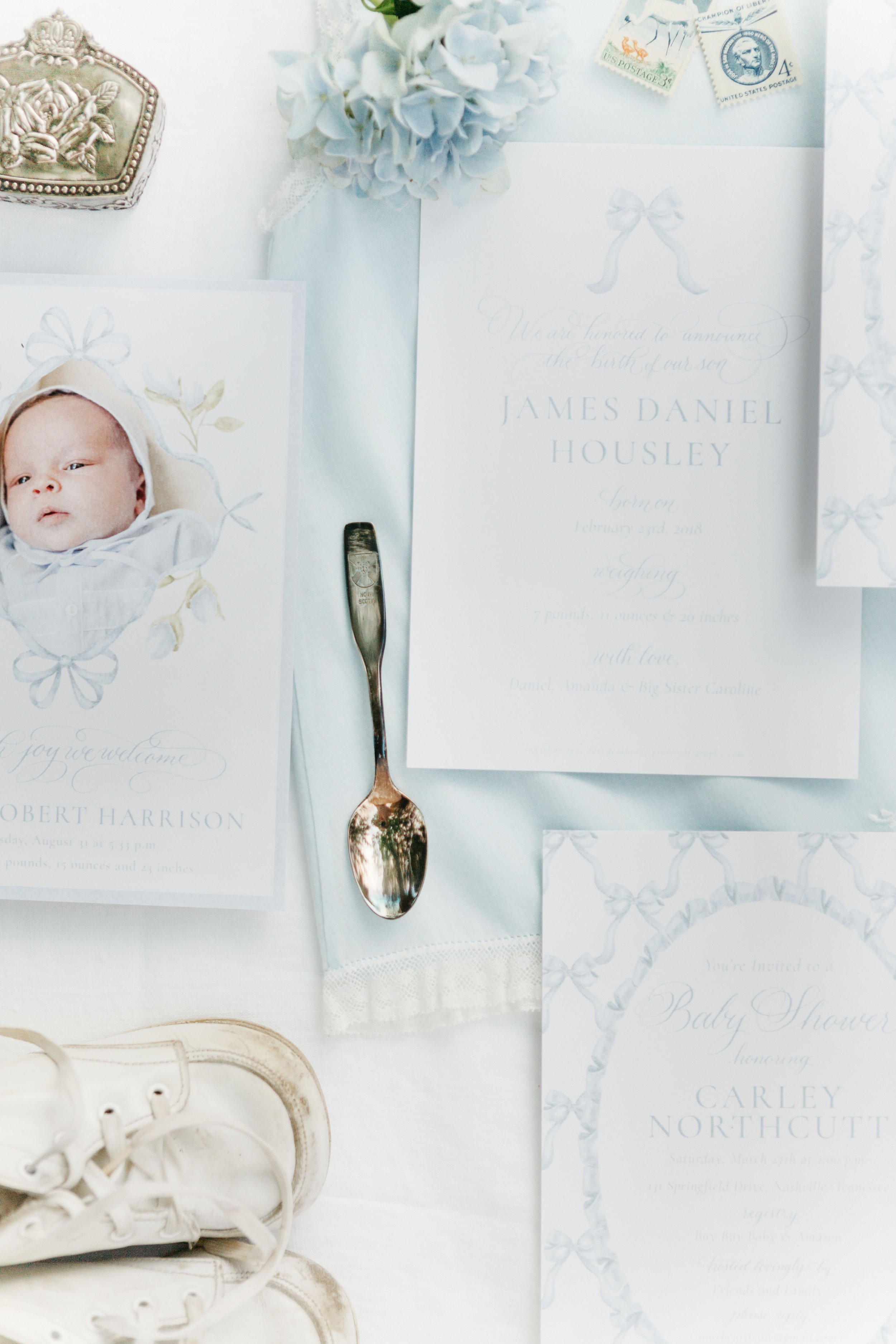 Wedding announcement and invitations for James Daniel Housley, featuring a photo of a newborn baby, a silver spoon, white flowers, and vintage-style stamps, with white sneakers visible in the bottom left corner.
