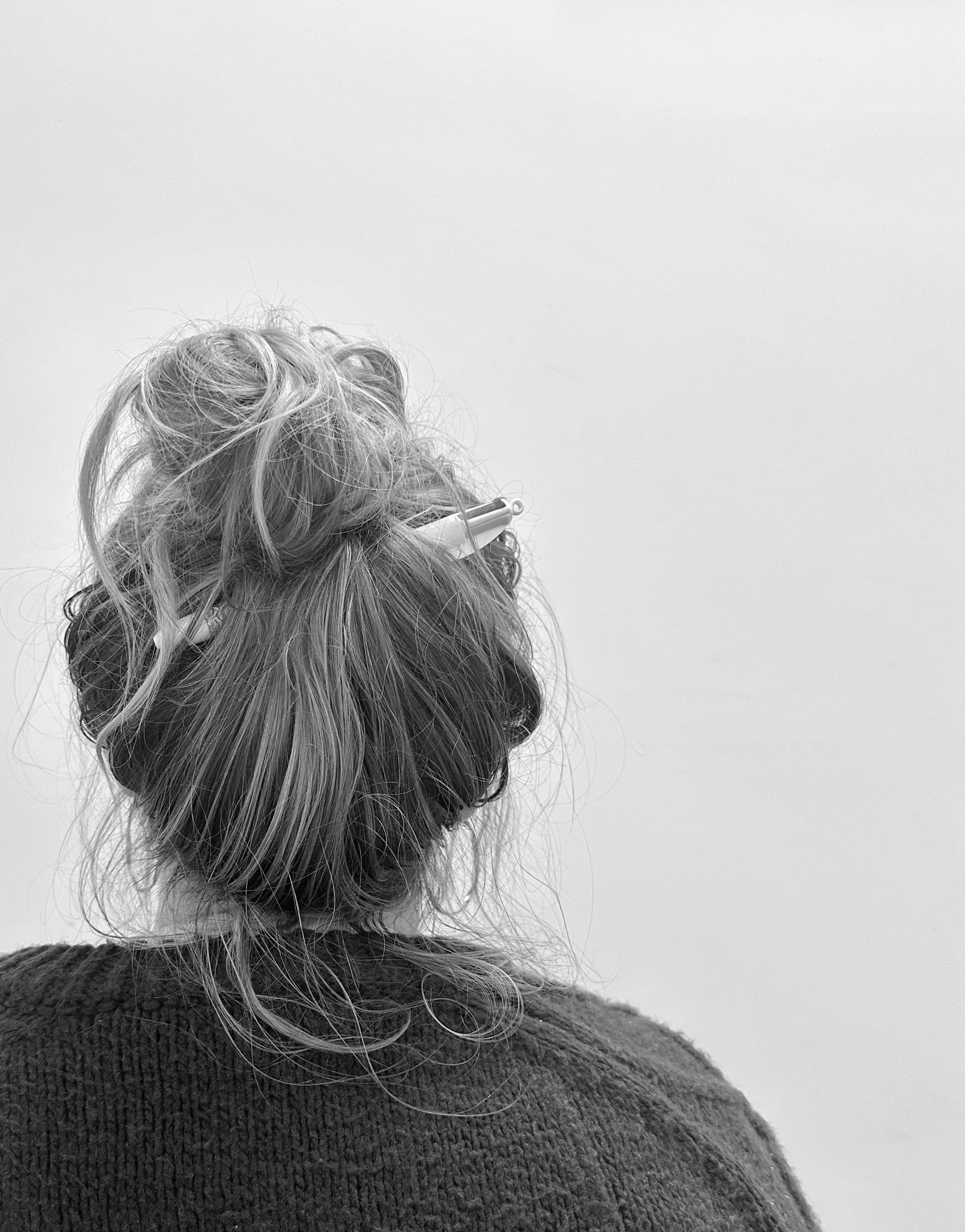 Image of the back of head. Hair is in a messy bun with a pen stuck through it.