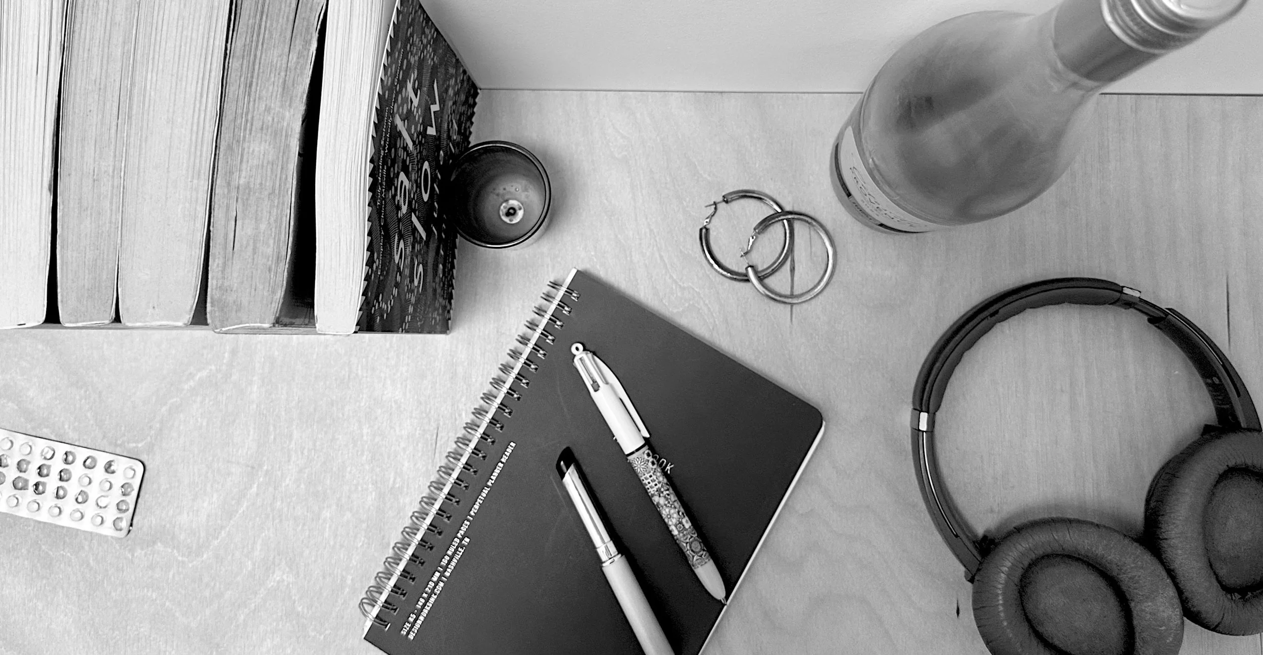 A selecion of objects that summarise my brain, from books, a notebook and pen, an open lipstick, a burnt out candle, a half drunk bottle of rosé wine, a pair of hoop earrrings and makeup stained headphones.