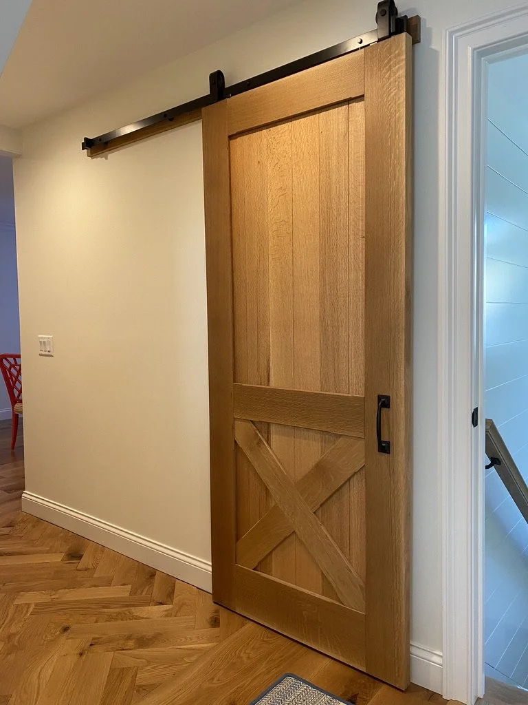 A wooden barn door sliding on a black metal track in an indoor home setting.