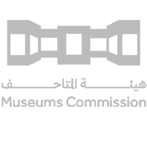Logo of the Museums Commission with a stylized depiction of a museum or building in black and gray, with Arabic text underneath and the English translation 'Museums Commission' at the bottom.
