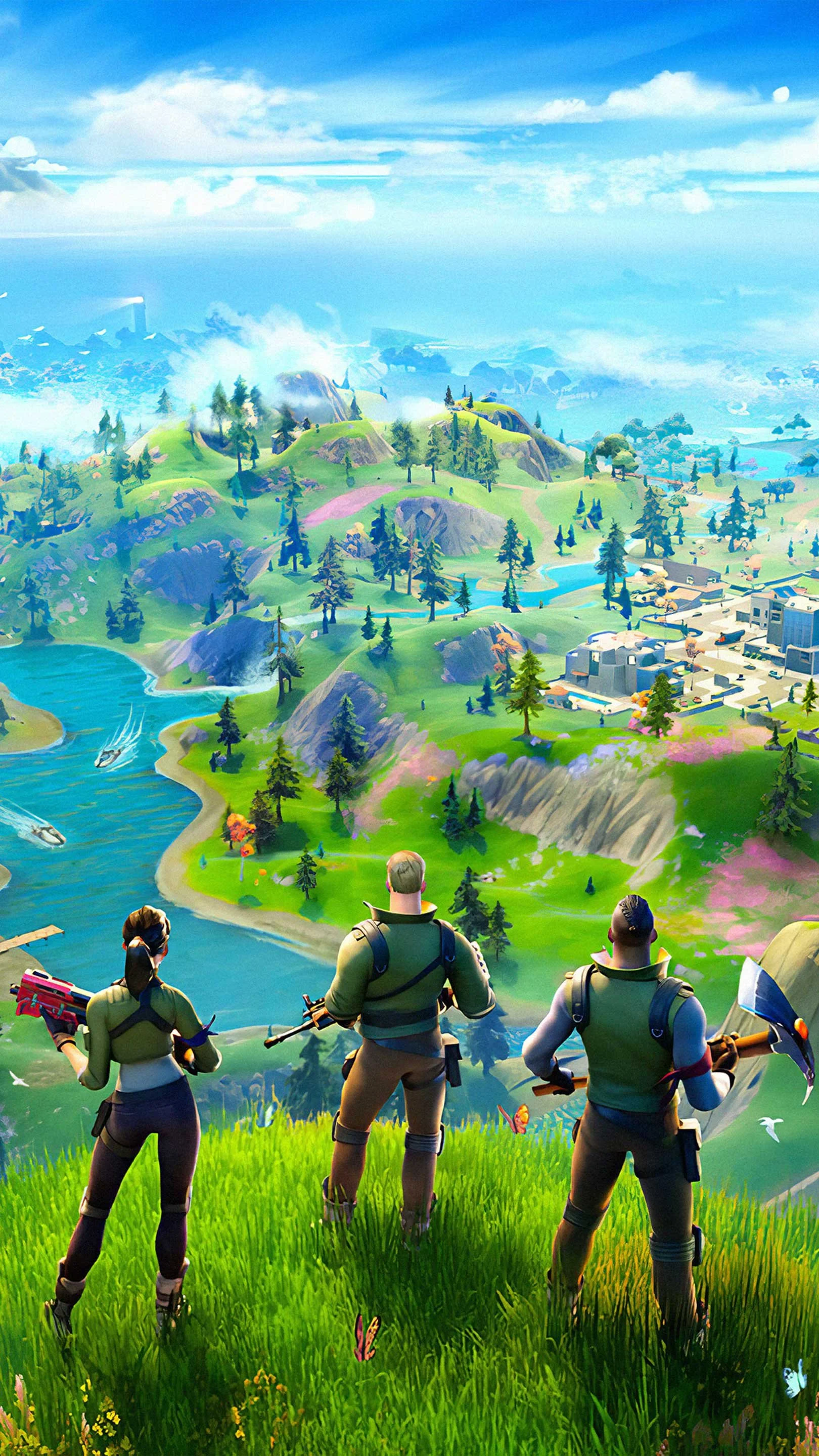 Three Fortnite characters standing on a grassy hill overlooking a vibrant, animated landscape with lakes, trees, mountains, and buildings.