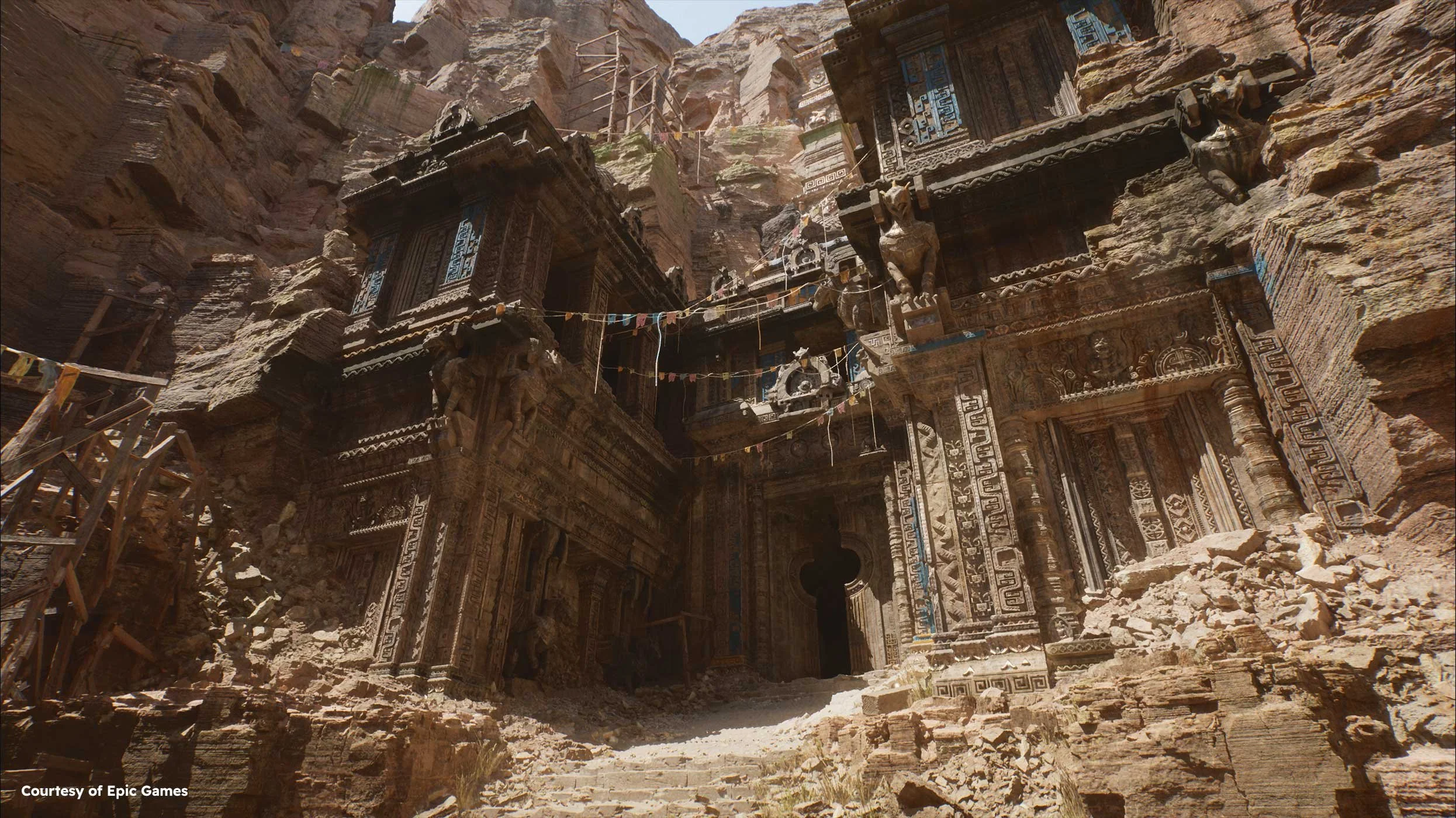 Ancient stone temple carved into a rocky cliff face, featuring intricate carvings and statues, with a dusty pathway leading up to its entrance.