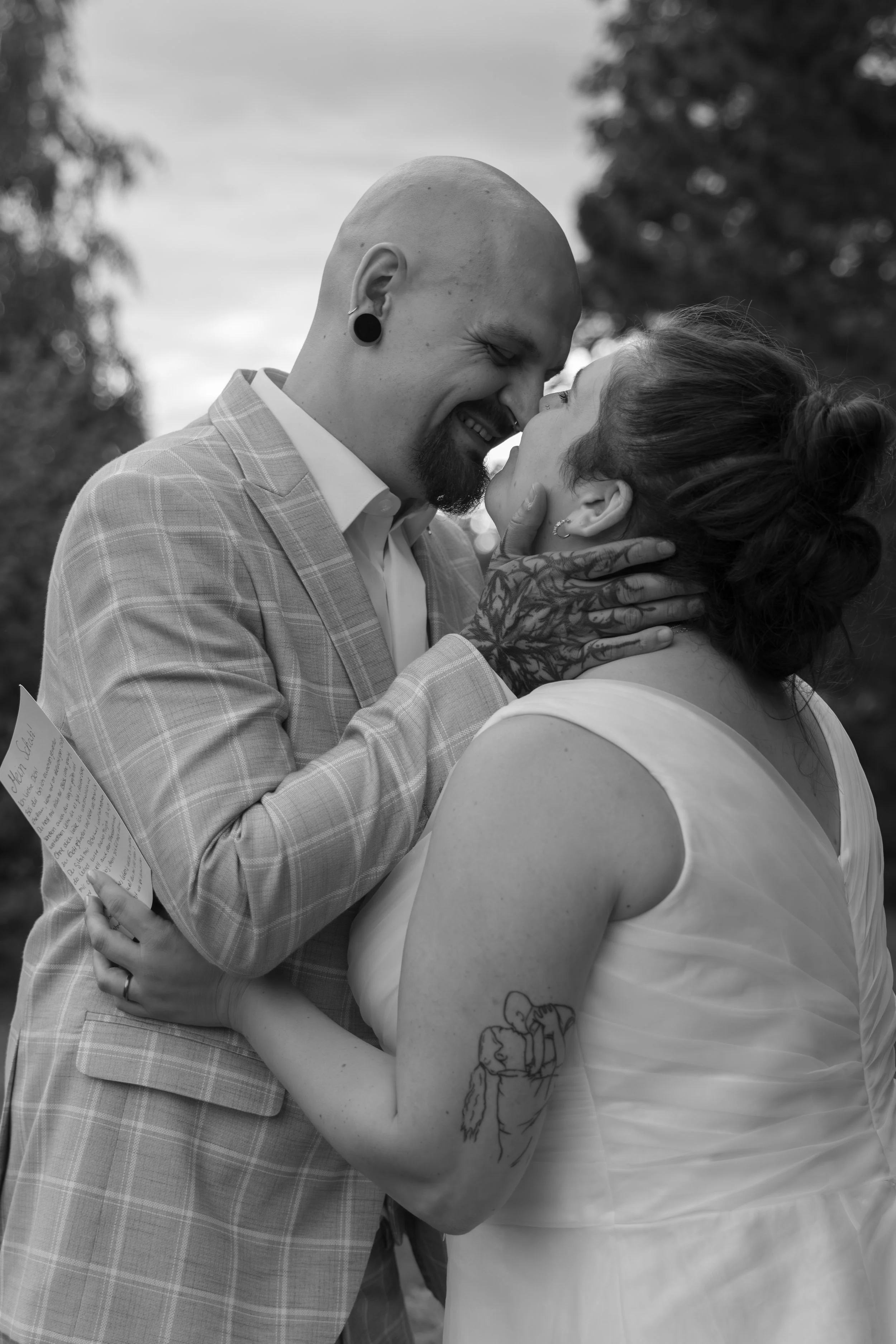 Ein Mann und eine Frau am Hochzeitstag, die sich tief verliebt ansehen, im Freien bei Sonnenuntergang, Schwarz-Weiß-Fotografie.