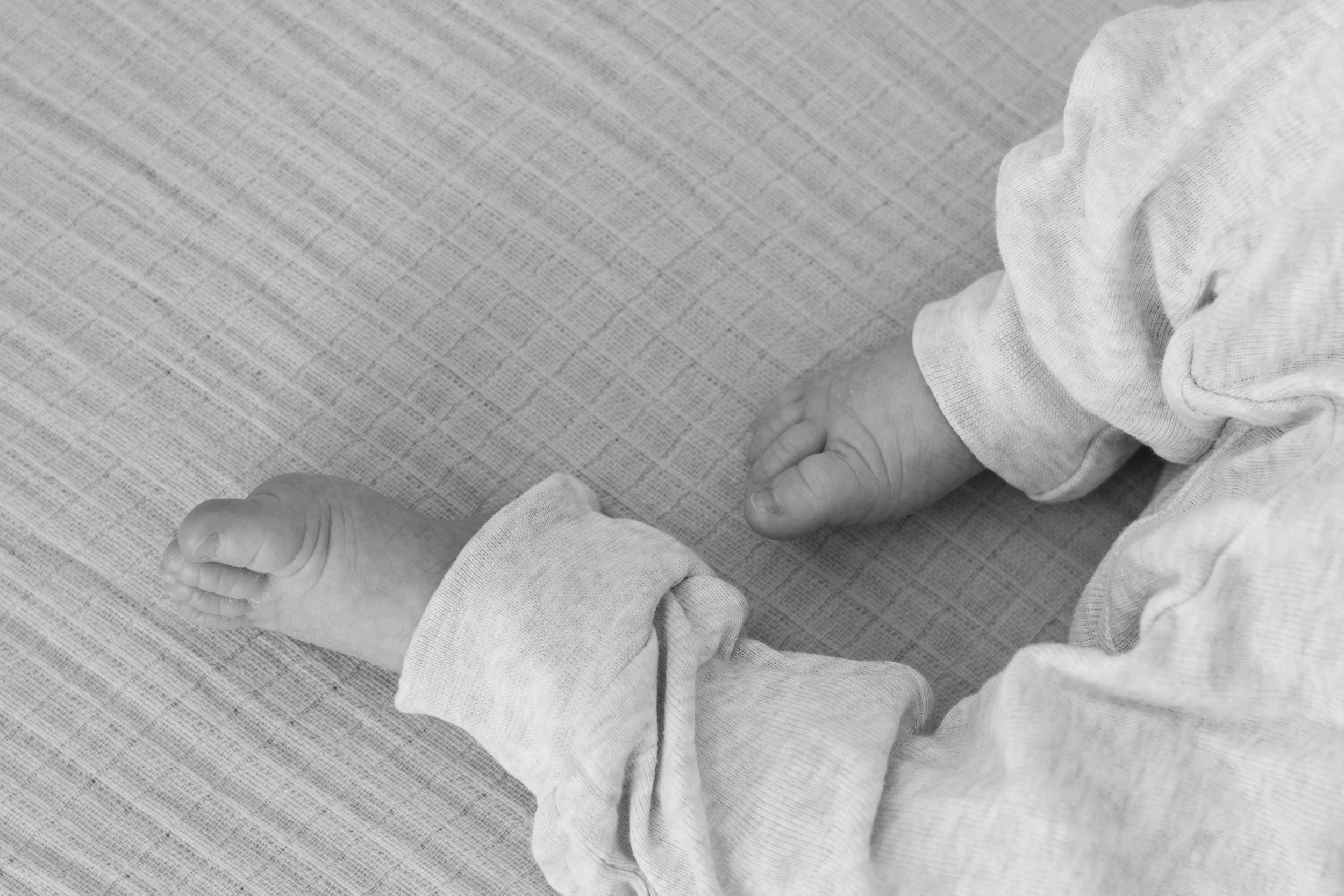 Nahaufnahme von Kinderfüßen auf einem hellen, texturierten Boden, die in einem langen Schlafanzug stecken.