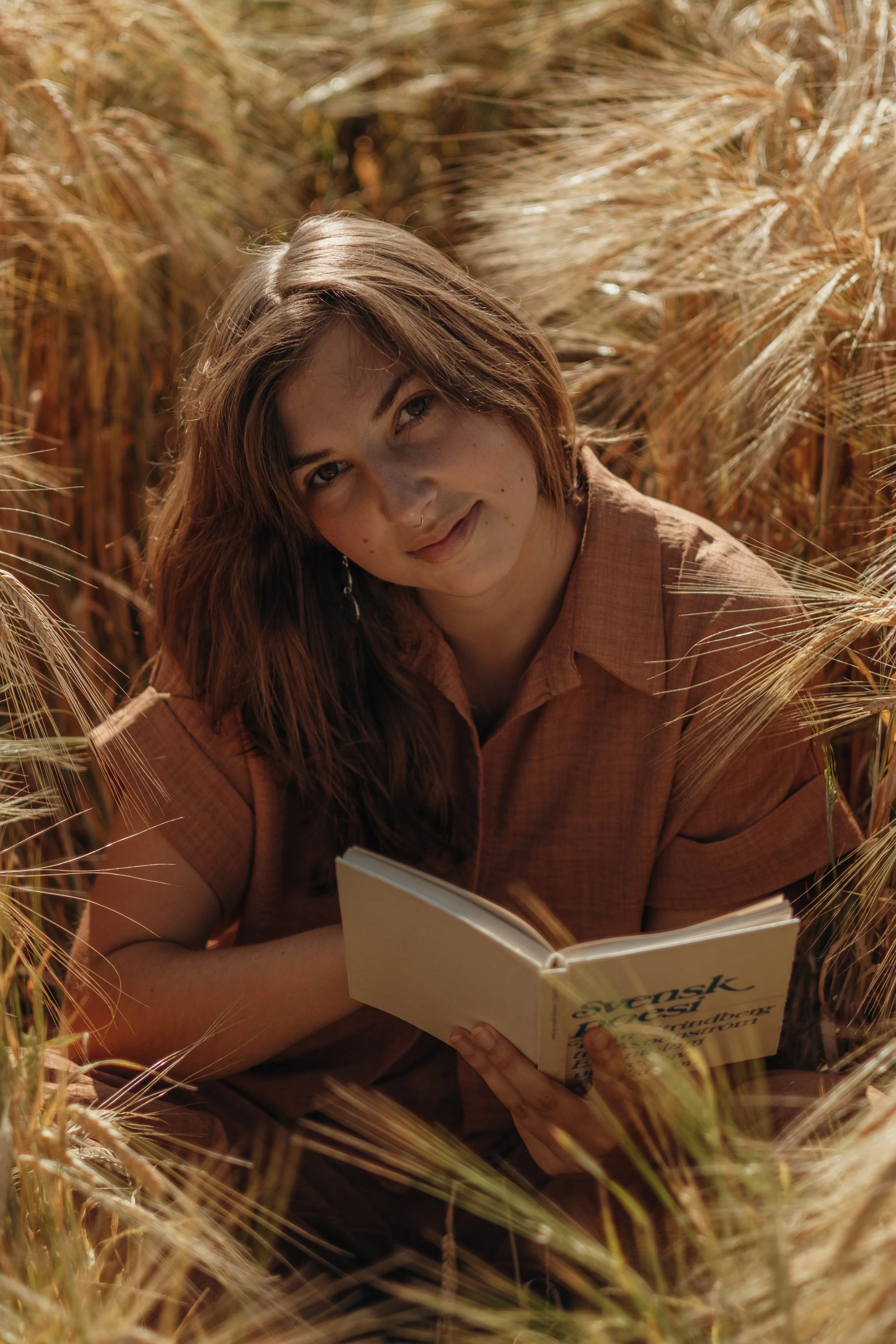 Junge Frau liest ein Buch im Getreidefeld bei Sonnenuntergang.