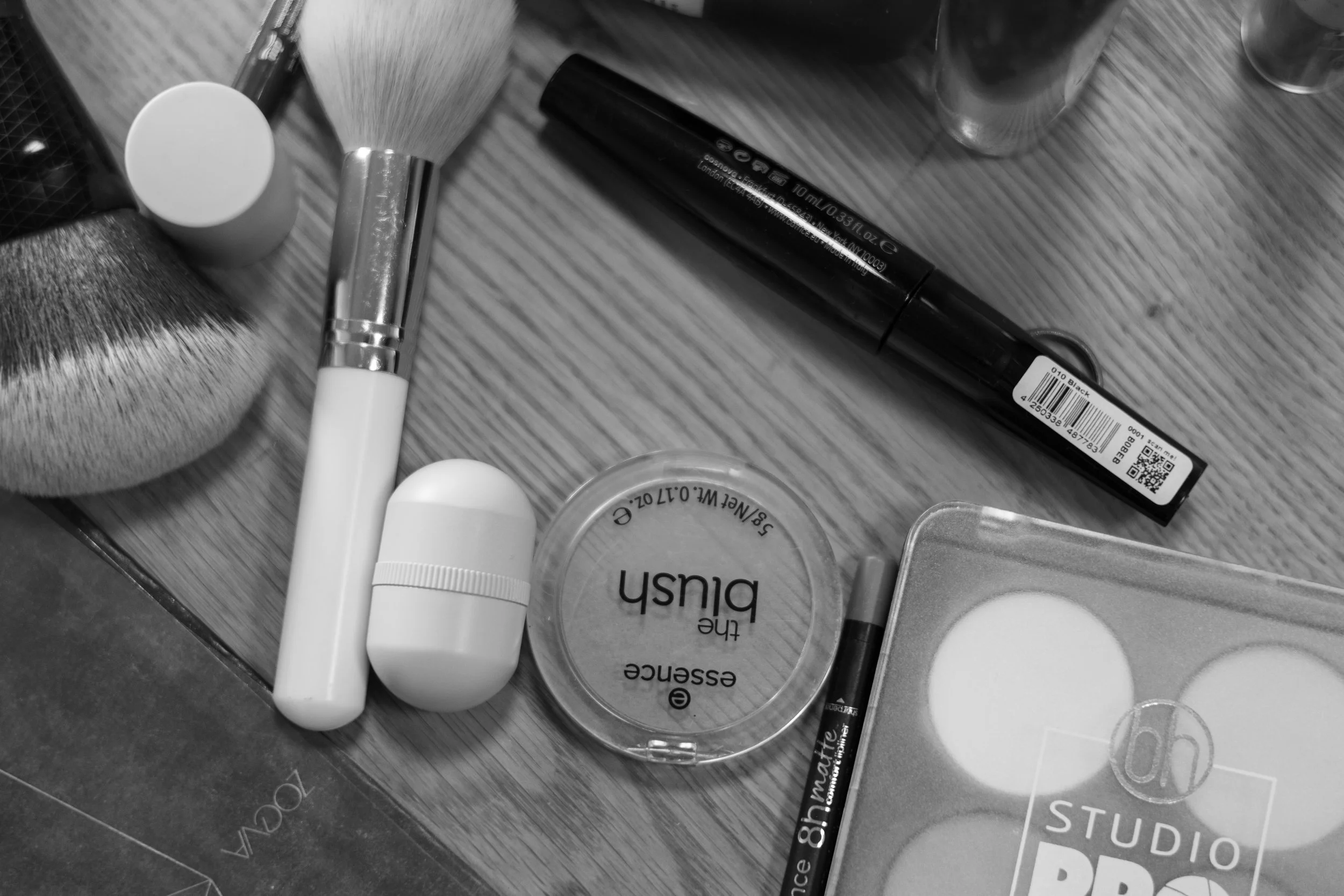 Make-up Pinsel, Lippenpflege, Kontaktlinsenbehälter, Make-up Produkt, Kosmetiktücher, Make-up Marker auf einem Holztisch.