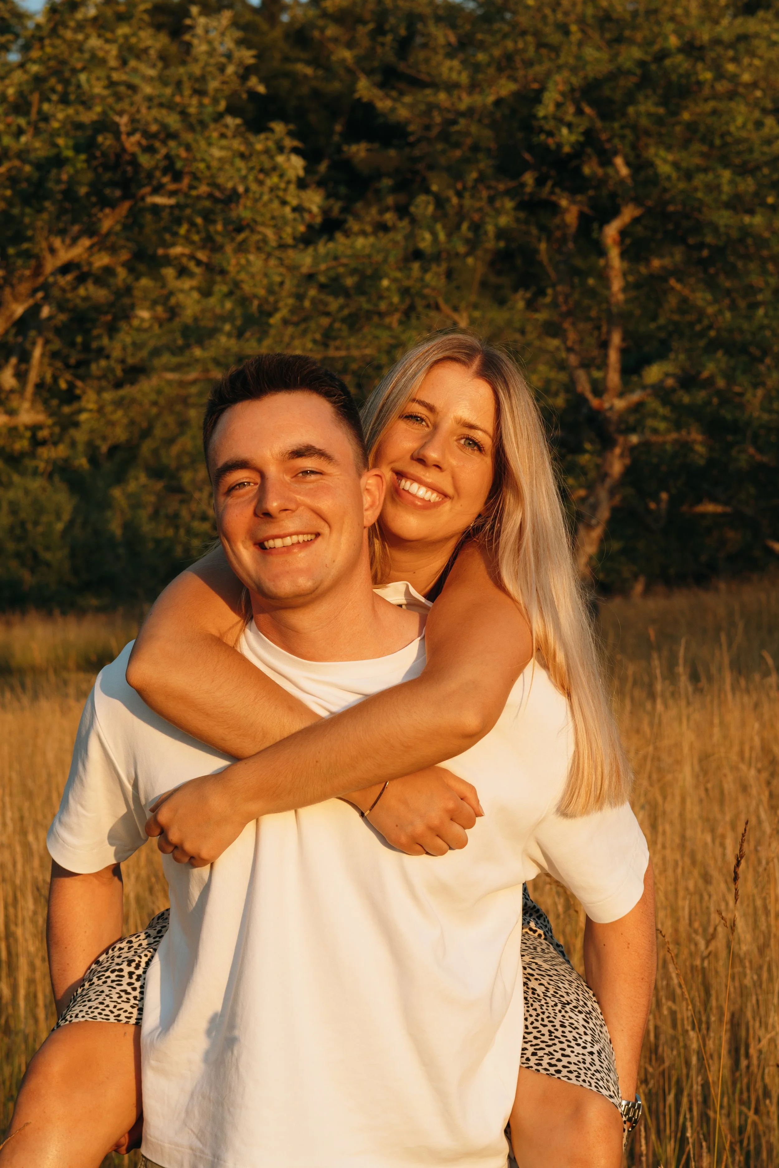 Ein glückliches Paar, das sich in einem Feld bei Sonnenuntergang umarmt.