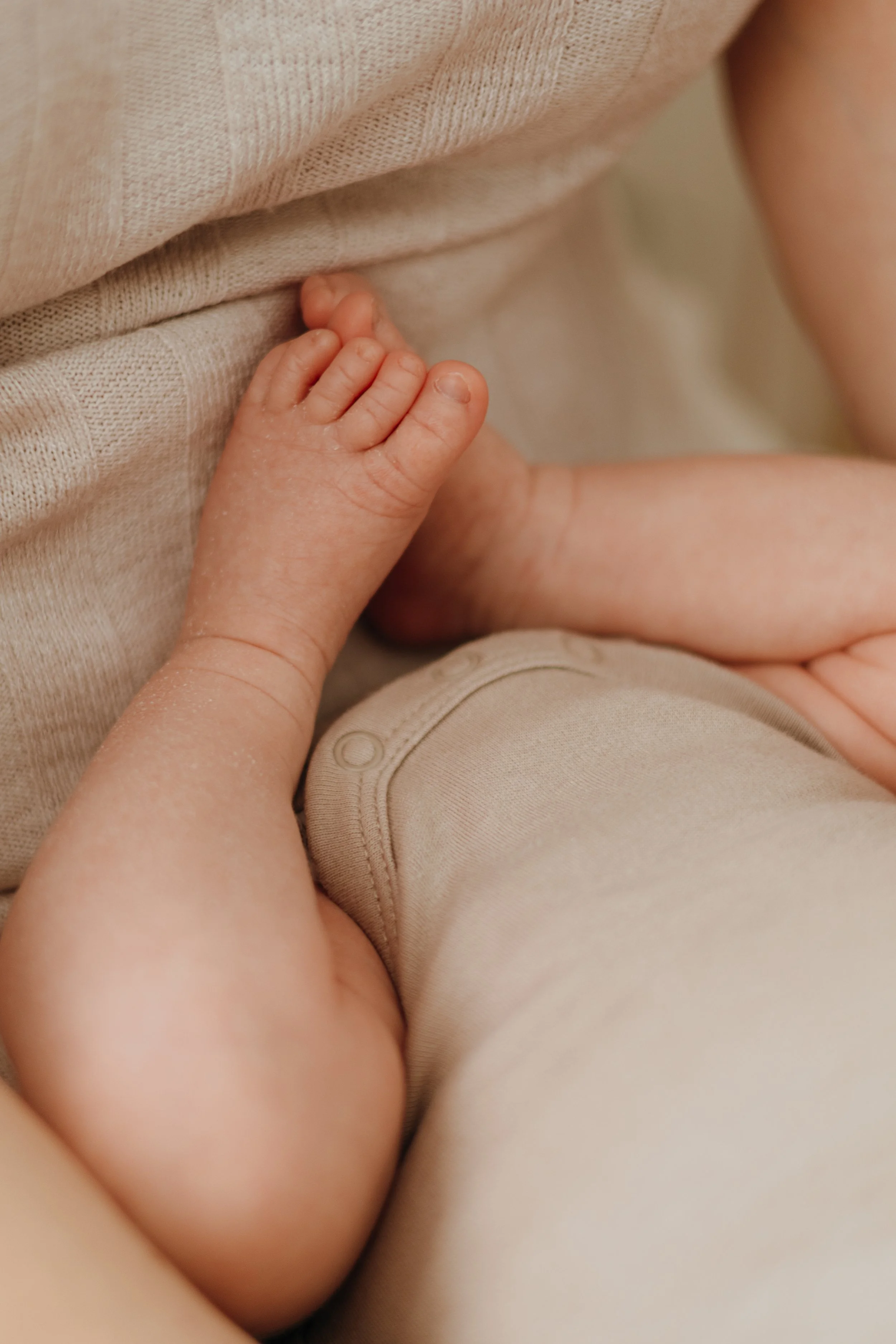 Nahaufnahme eines Babyhändchens, das sich an die Kleidung eines Erwachsenen schmiegt.