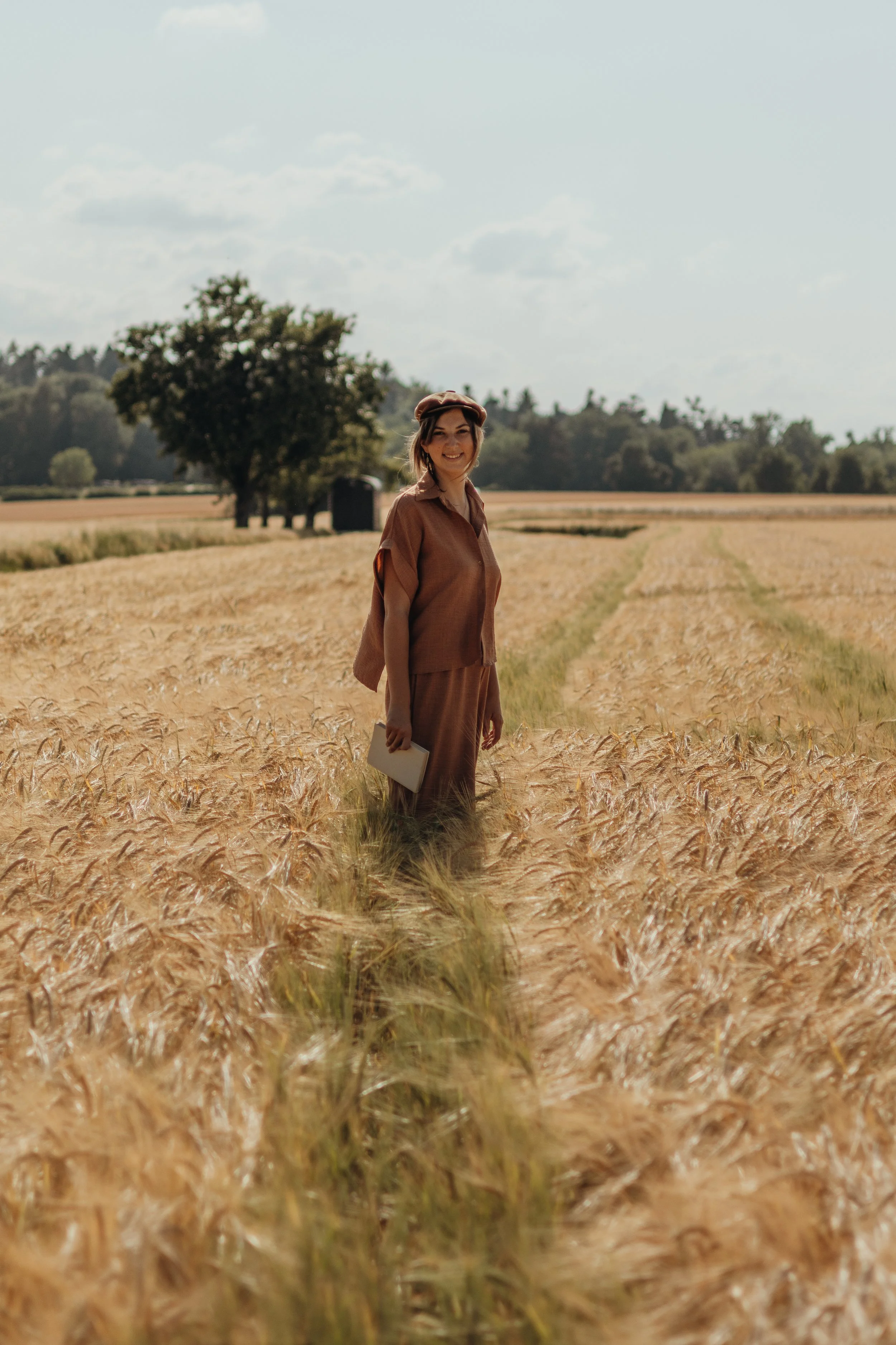 Eine Frau steht in einem Weizenfeld an einem sonnigen Tag