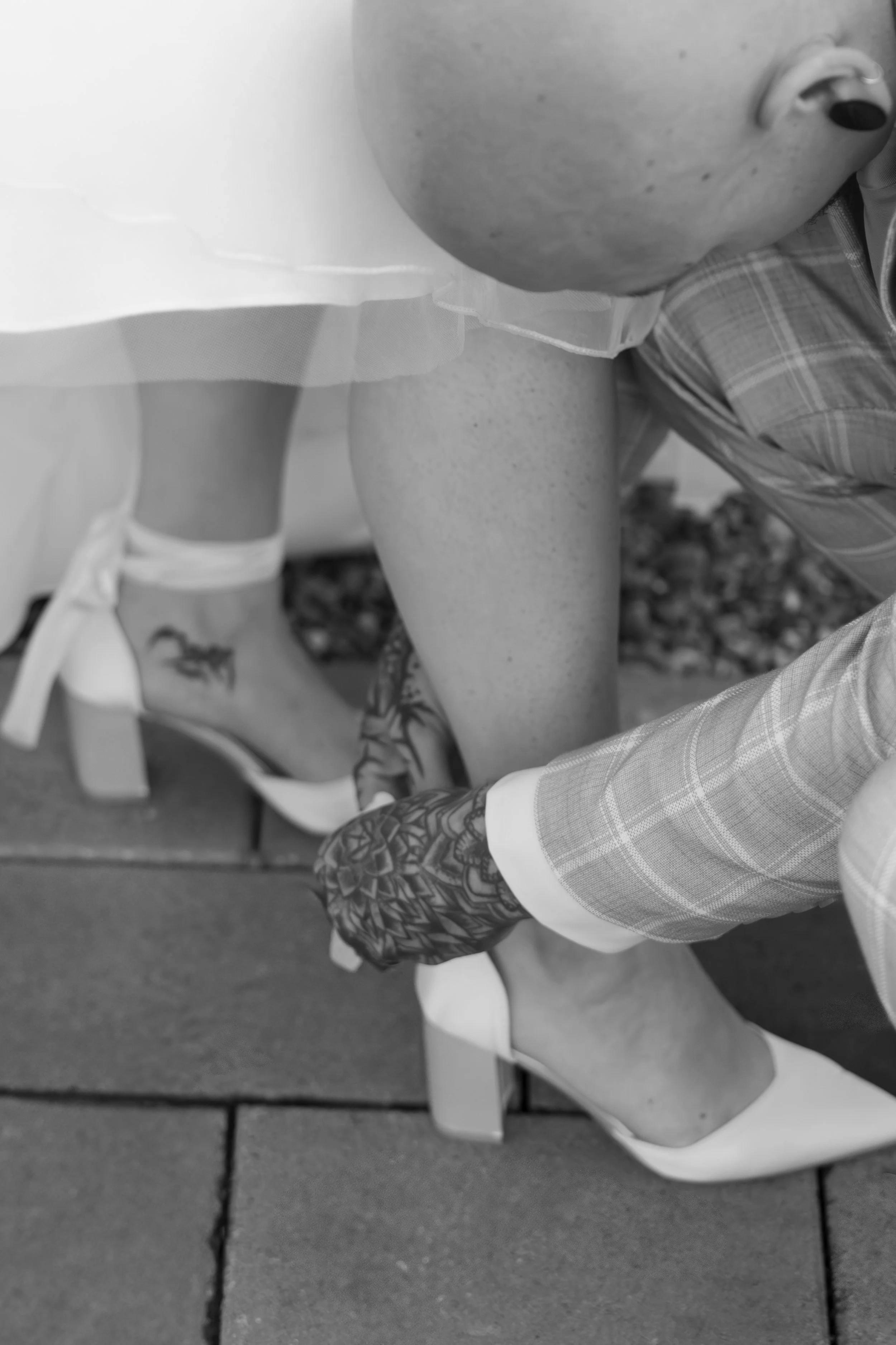 Ein Brautpaar bei der Schuhüberreichung während einer Hochzeitszeremonie, im Schwarz-Weiß-Foto.