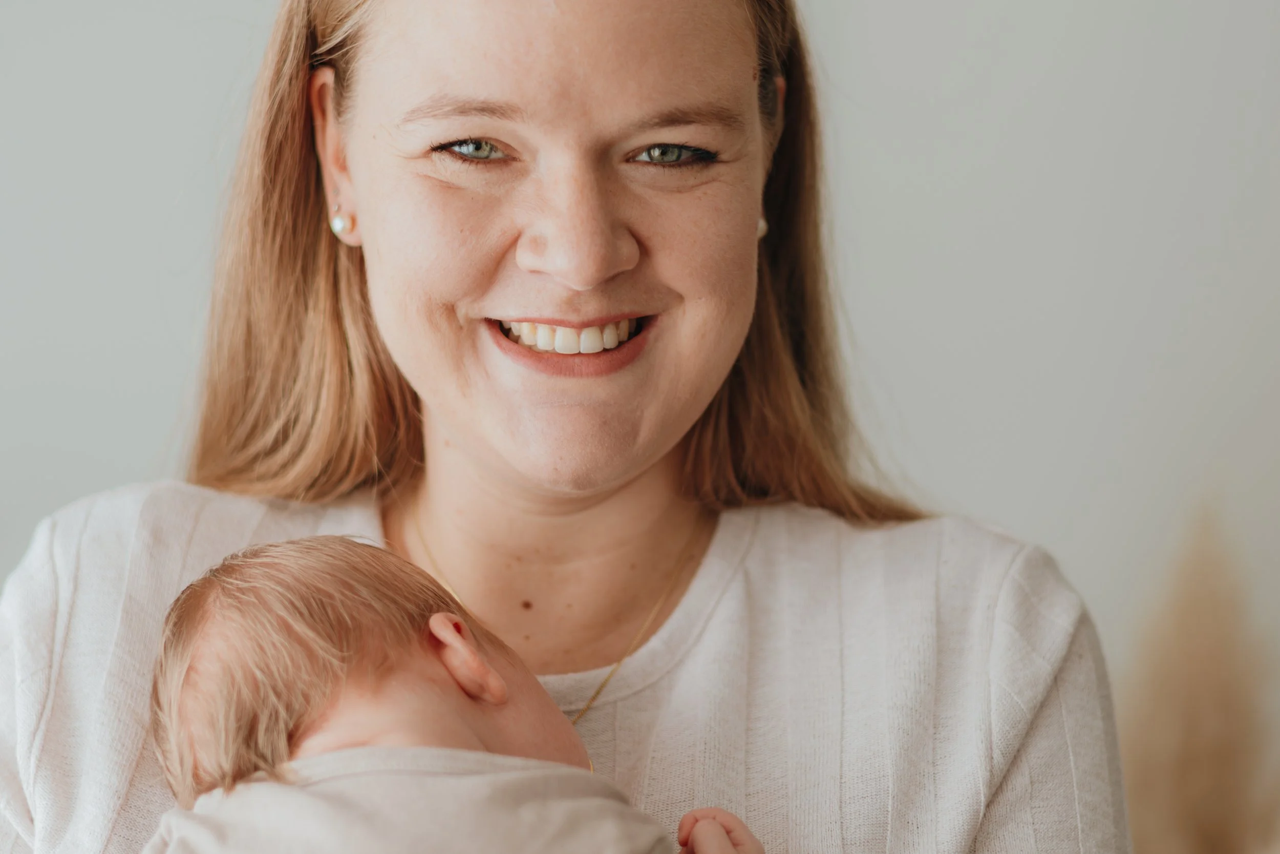 Eine lächelnde Frau hält ein schlafendes Baby auf dem Arm.