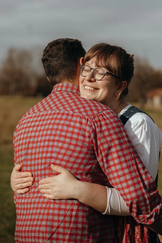 Zwei Menschen umarmen sich im Freien, lachend und glücklich.