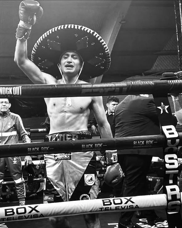 Boxer wearing a sombrero celebrating in the boxing ring after a match.