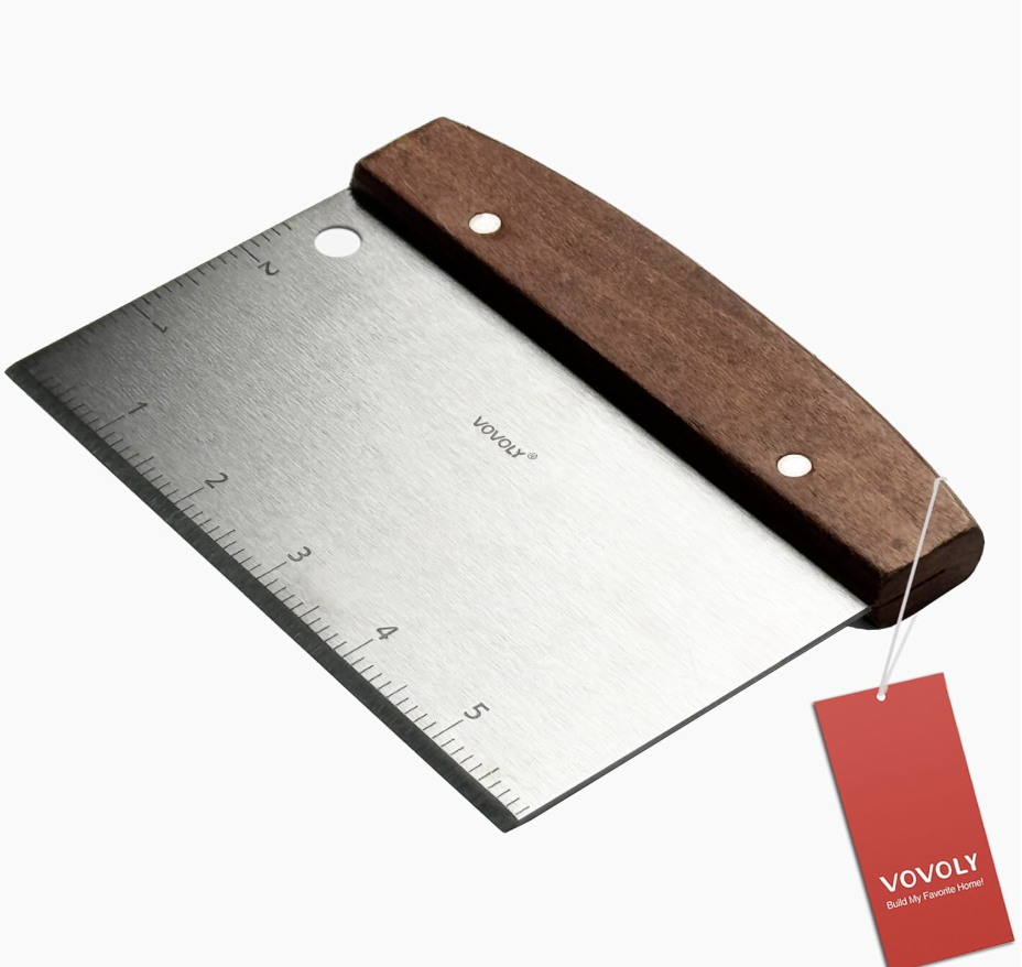 A professional-grade stainless steel bench scraper with a wooden handle and measuring scale, used for portioning brioche dough at M7 Trading Post.